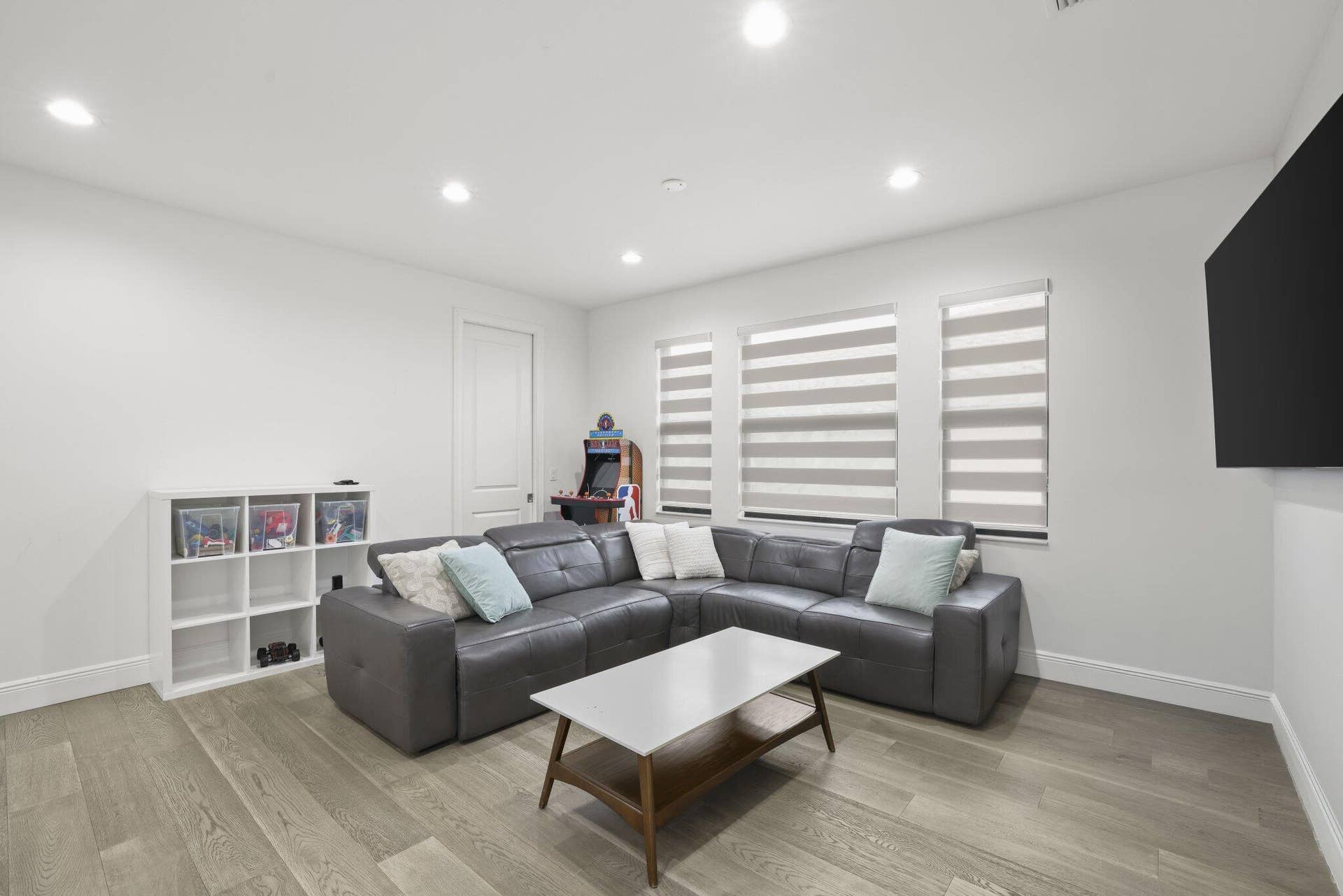 Recessed ceiling lighting, wood-finish flooring, white walls, and multiple windows with blinds