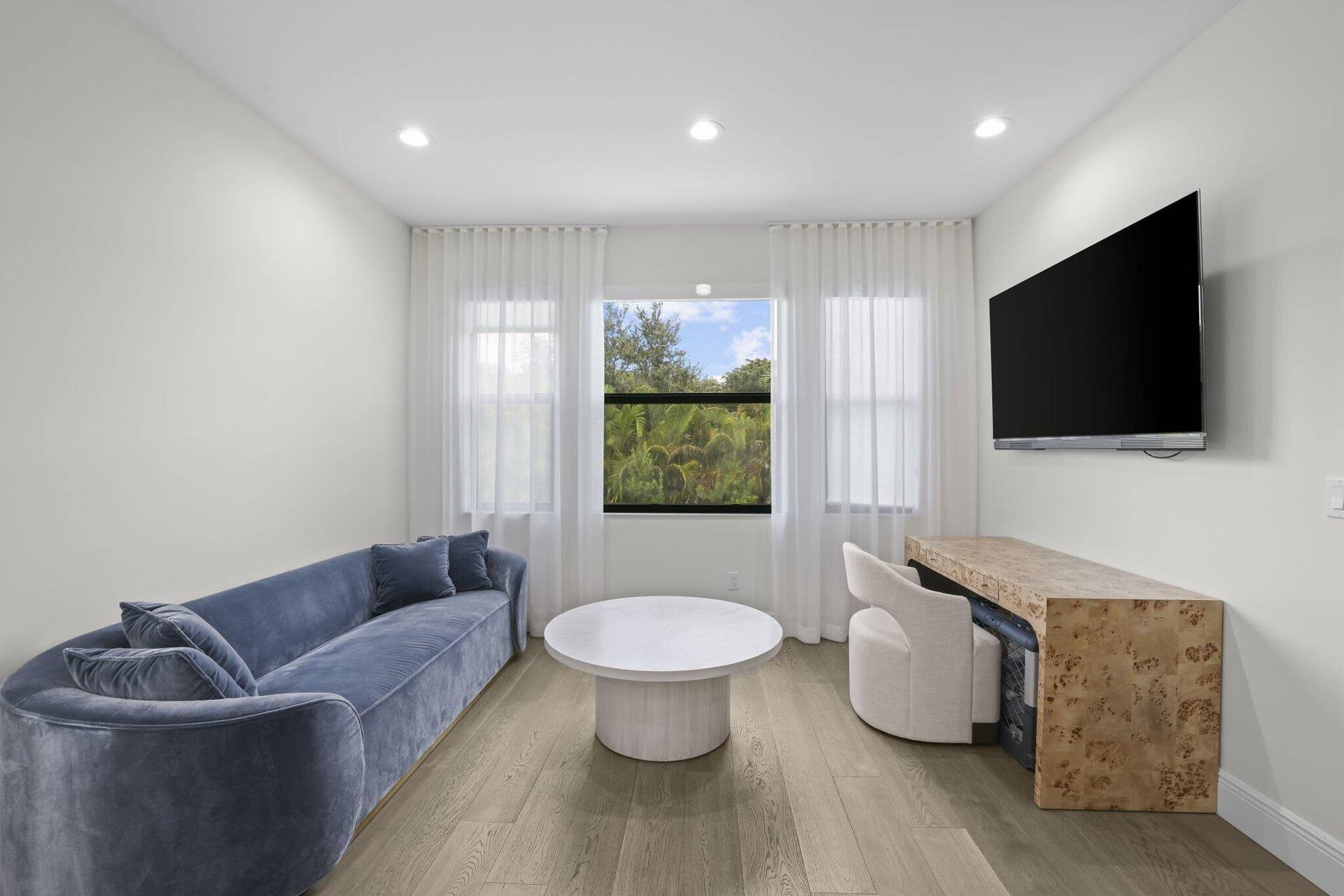 Recessed lighting, wood-finish flooring, multiple windows with sheers, and a built-in console