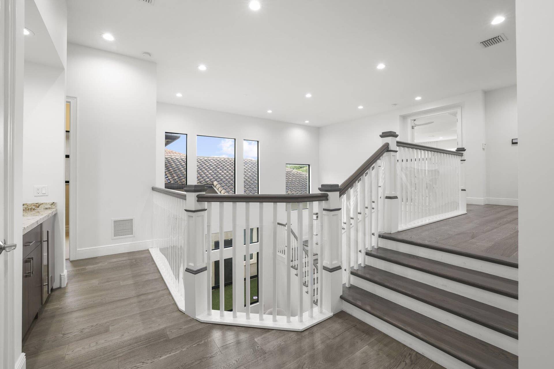 Open landing with wood-finish flooring, white walls, and recessed lighting