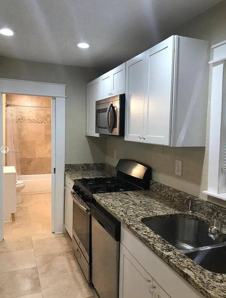 Kitchen featuring white shaker-style cabinetry, stone countertops, stainless steel appliances, and recessed lighting