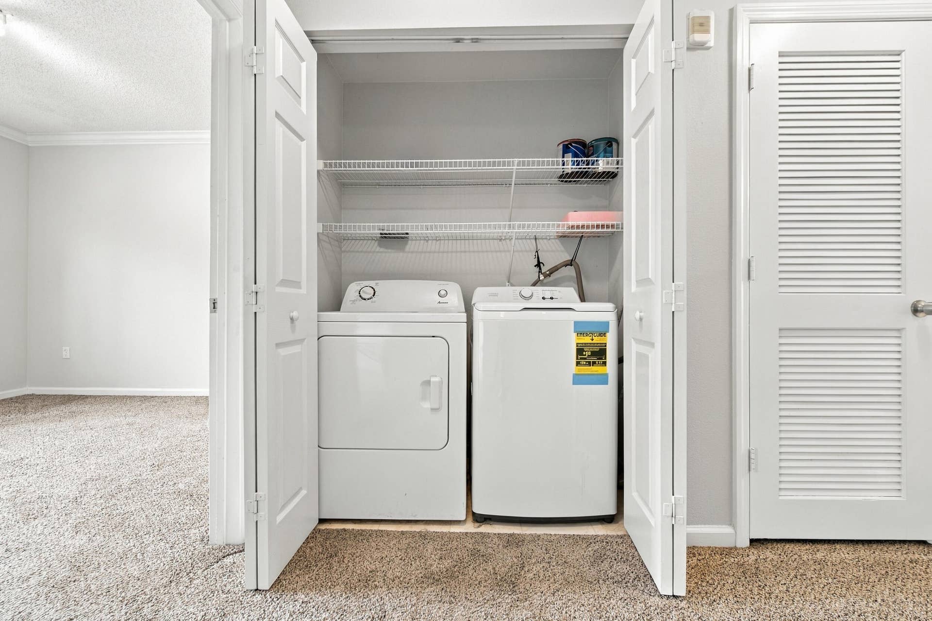 533 NE 3RD Avenue, #202, Fort Lauderdale, FL 33301 Laundry closet featuring side-by-side appliances, dual wire shelving, and double louvered doors