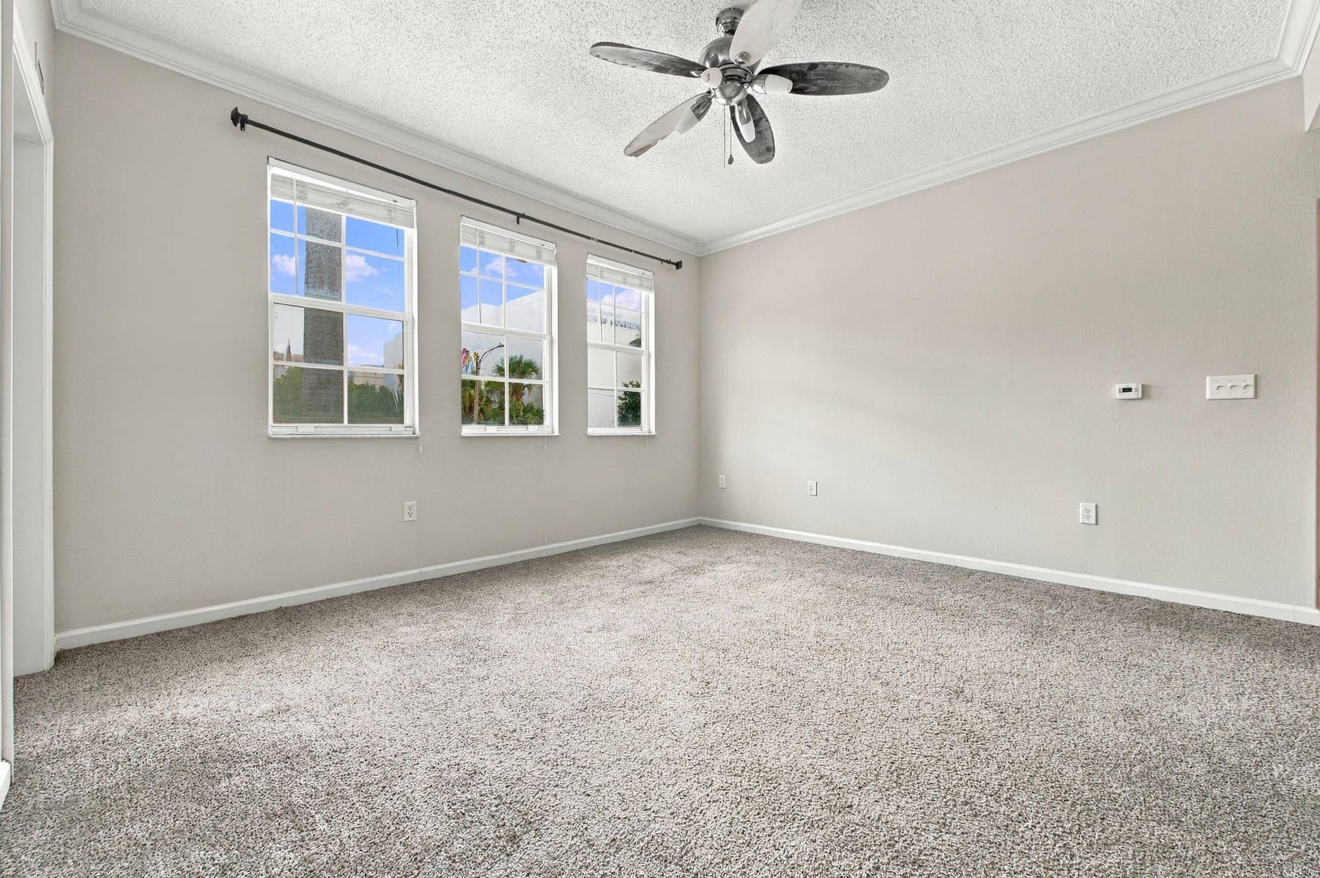 533 NE 3RD Avenue, #202, Fort Lauderdale, FL 33301 Neutral-toned interior featuring wall-to-wall carpeting, three multi-pane windows, crown molding, and a ceiling fan