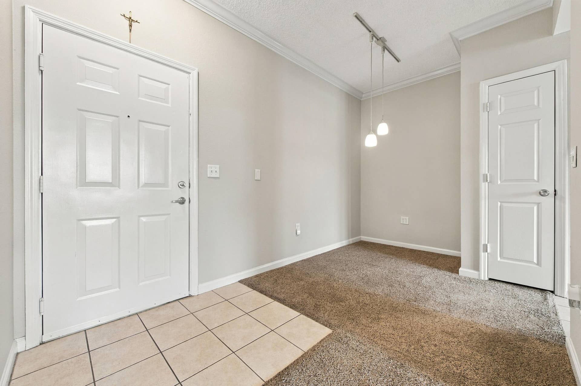 533 NE 3RD Avenue, #202, Fort Lauderdale, FL 33301 Entryway featuring neutral-toned tile flooring, carpeted floor surfaces, crown molding, a multi-panel door, and a suspended track lighting fixture