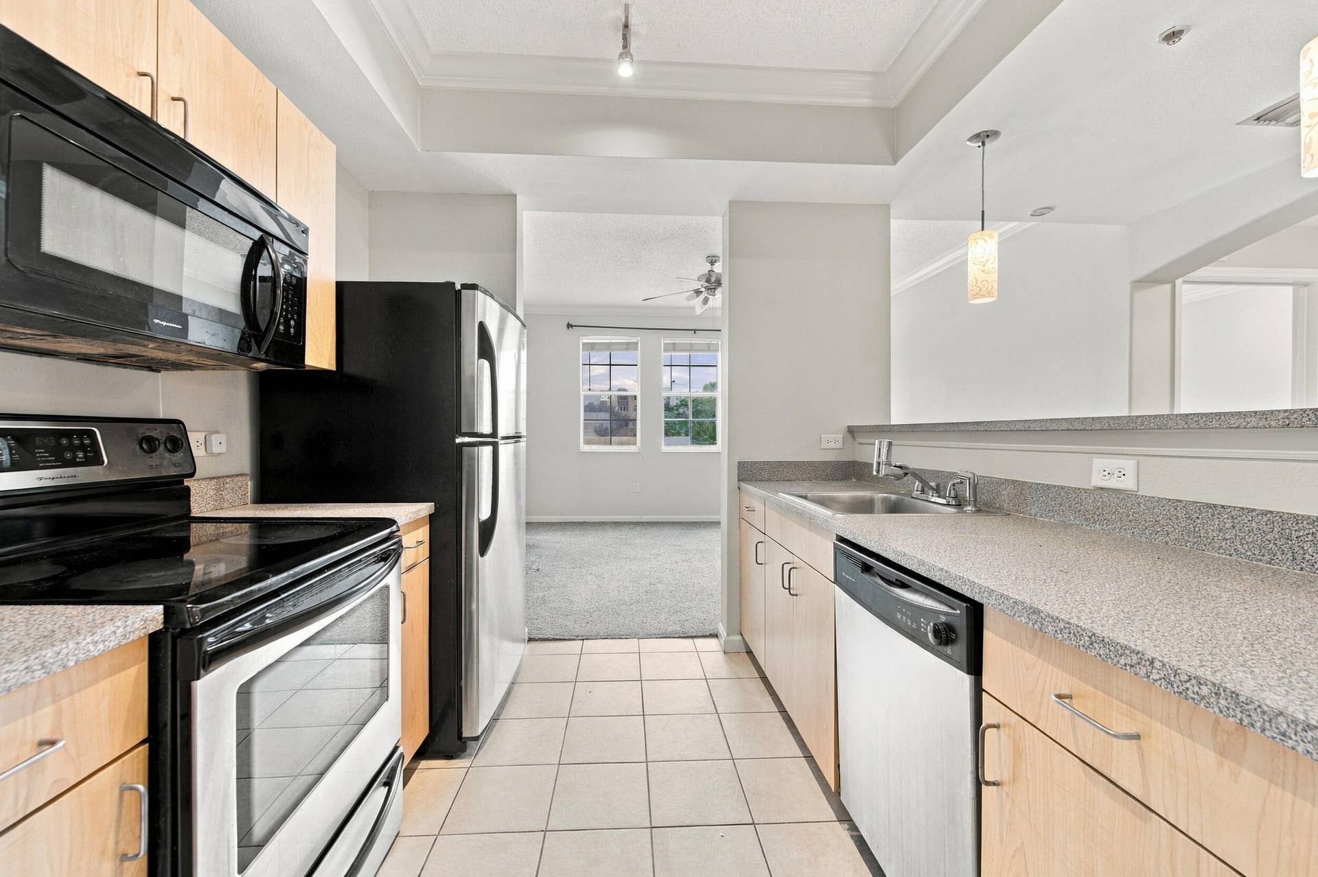 533 NE 3RD Avenue, #202, Fort Lauderdale, FL 33301 Kitchen featuring light wood-finish cabinetry, solid surface countertops, stainless steel appliances, ceramic tile flooring, and a breakfast bar