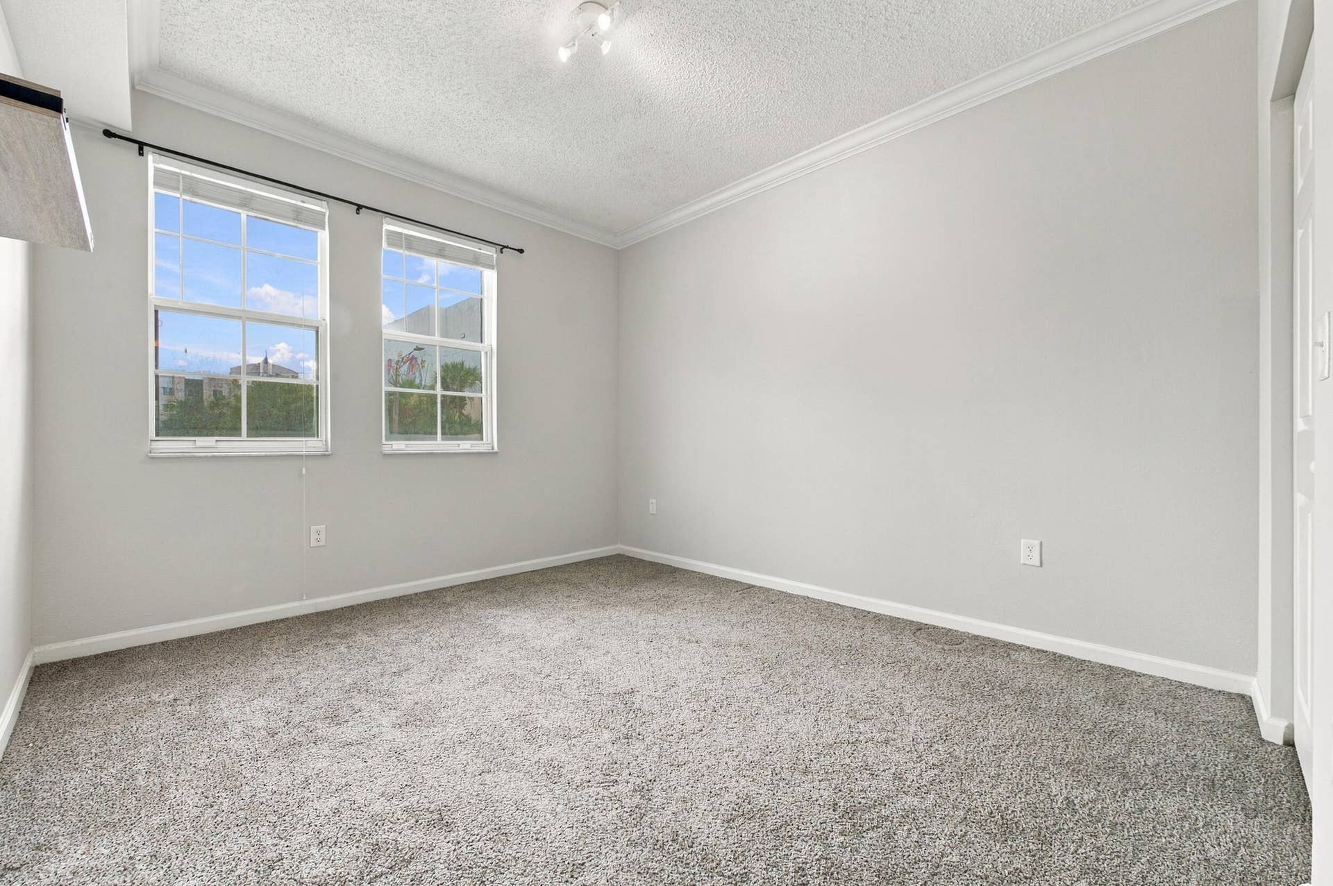 533 NE 3RD Avenue, #202, Fort Lauderdale, FL 33301 Neutral-toned interior featuring dual double-hung windows, crown molding, and wall-to-wall carpeting