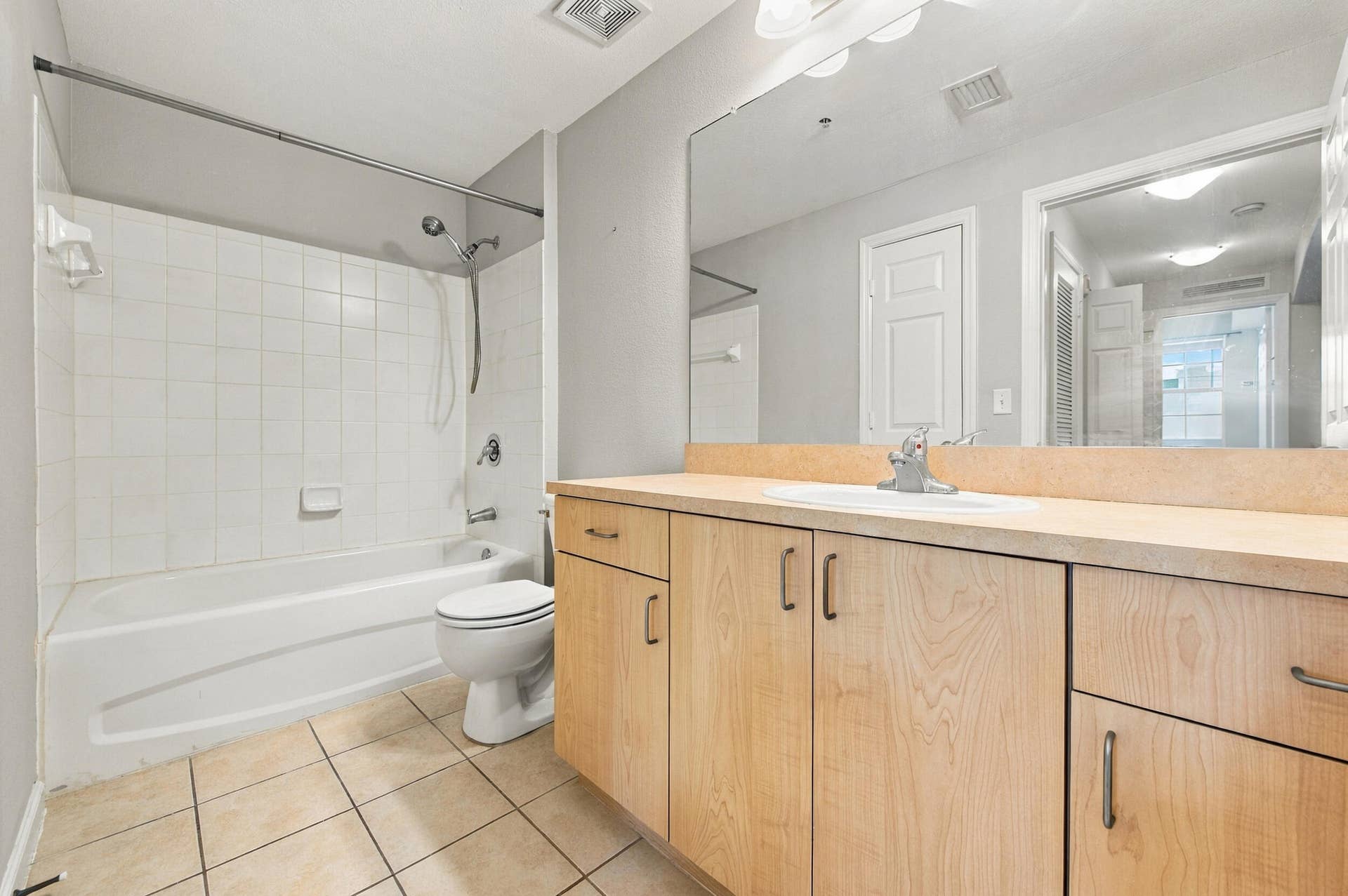 533 NE 3RD Avenue, #202, Fort Lauderdale, FL 33301 Bathroom featuring a light wood-finish vanity, solid-surface countertop with an integrated basin, oversized wall-mounted mirror, and tile flooring