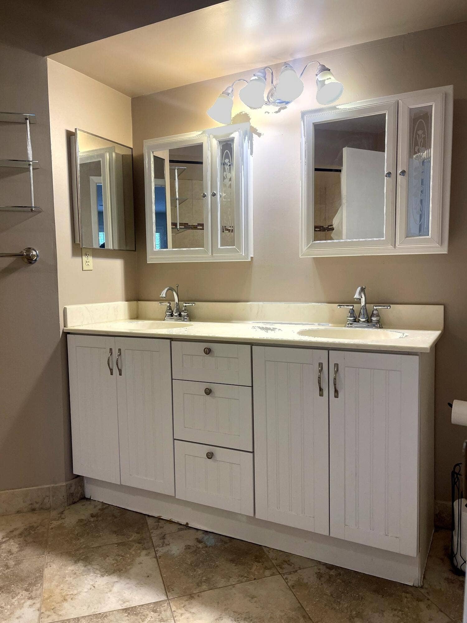 Double vanity featuring white cabinetry, stone-finish countertops with dual integrated sinks, polished chrome hardware, and wall-mounted medicine cabinets