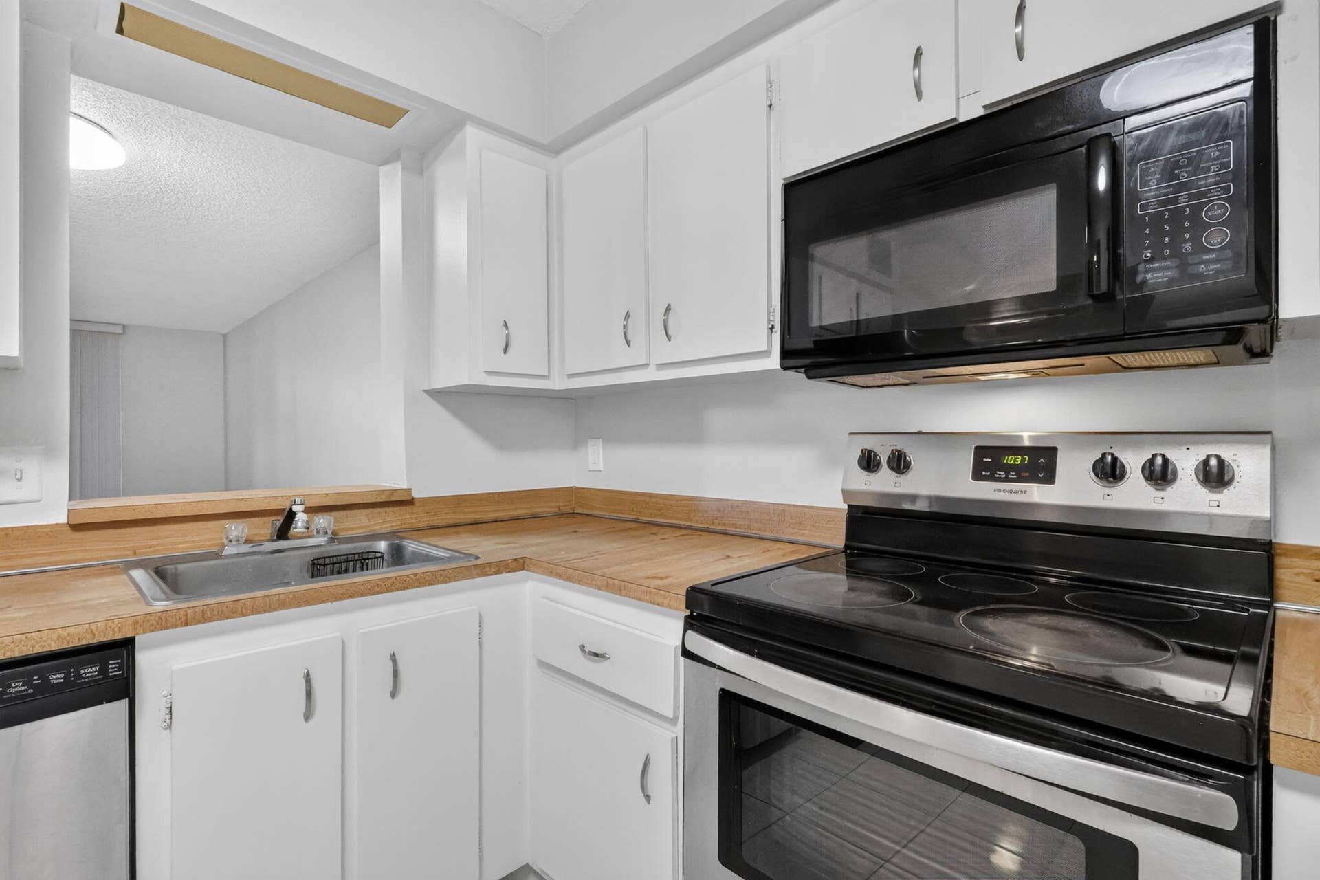 14527 BONAIRE Boulevard, #109, Delray Beach, FL 33446 Kitchen featuring white cabinetry, wood-finish countertops, stainless steel sink, and built-in black and stainless steel appliances
