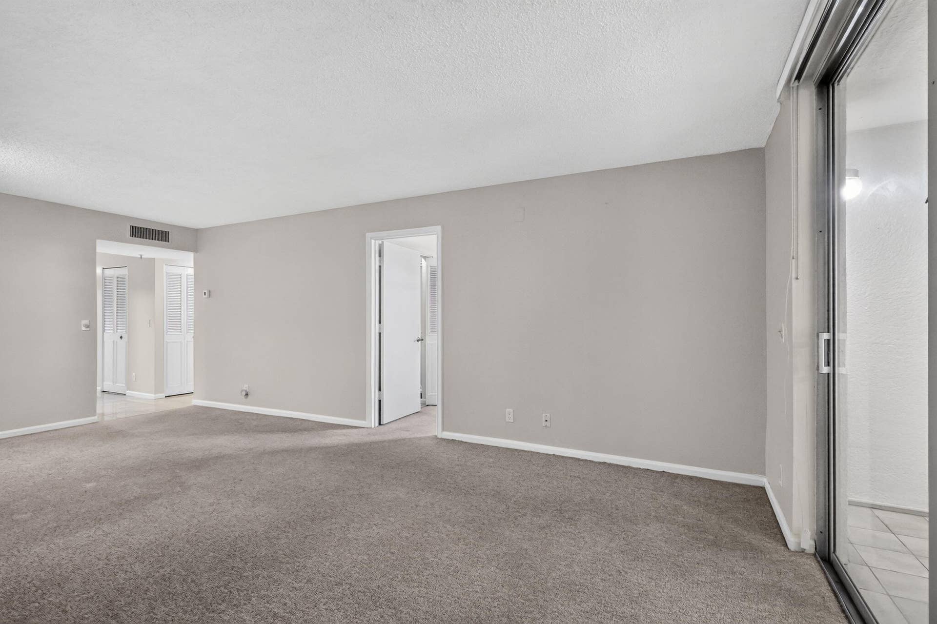 14527 BONAIRE Boulevard, #109, Delray Beach, FL 33446 Neutral-toned interior featuring wall-to-wall carpeting, sliding glass doors, and interior doorways with white trim