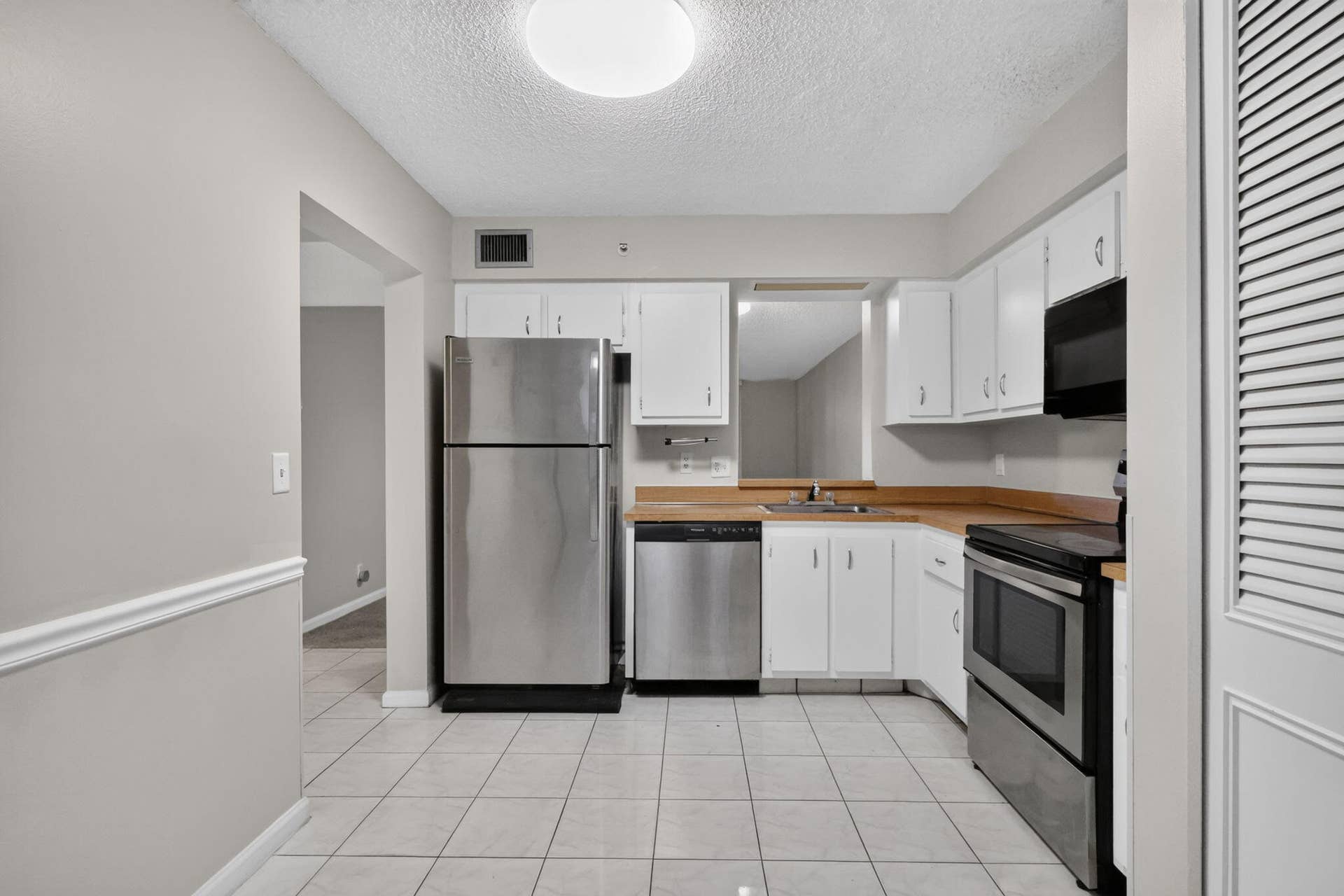 14527 BONAIRE Boulevard, #109, Delray Beach, FL 33446 Kitchen featuring white cabinetry, stainless steel appliances, solid-surface countertops, and tile flooring
