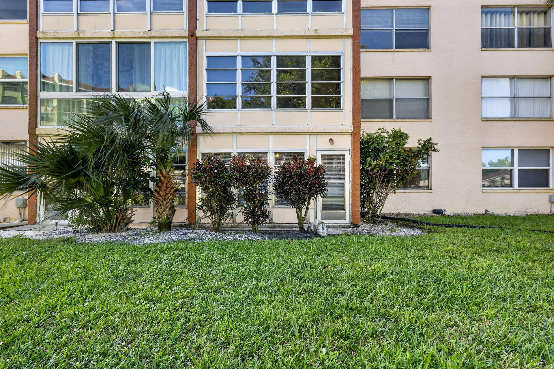 14527 BONAIRE Boulevard, #109, Delray Beach, FL 33446 Multi-story exterior featuring a grid-patterned facade, expansive window banks, integrated glass-paneled entry, and manicured landscaping