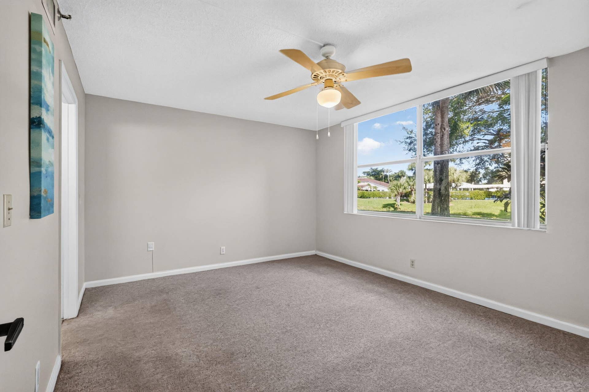 14527 BONAIRE Boulevard, #109, Delray Beach, FL 33446 Neutral-toned interior space featuring neutral wall-to-wall carpeting, large multi-pane windows, and a ceiling fan with integrated lighting