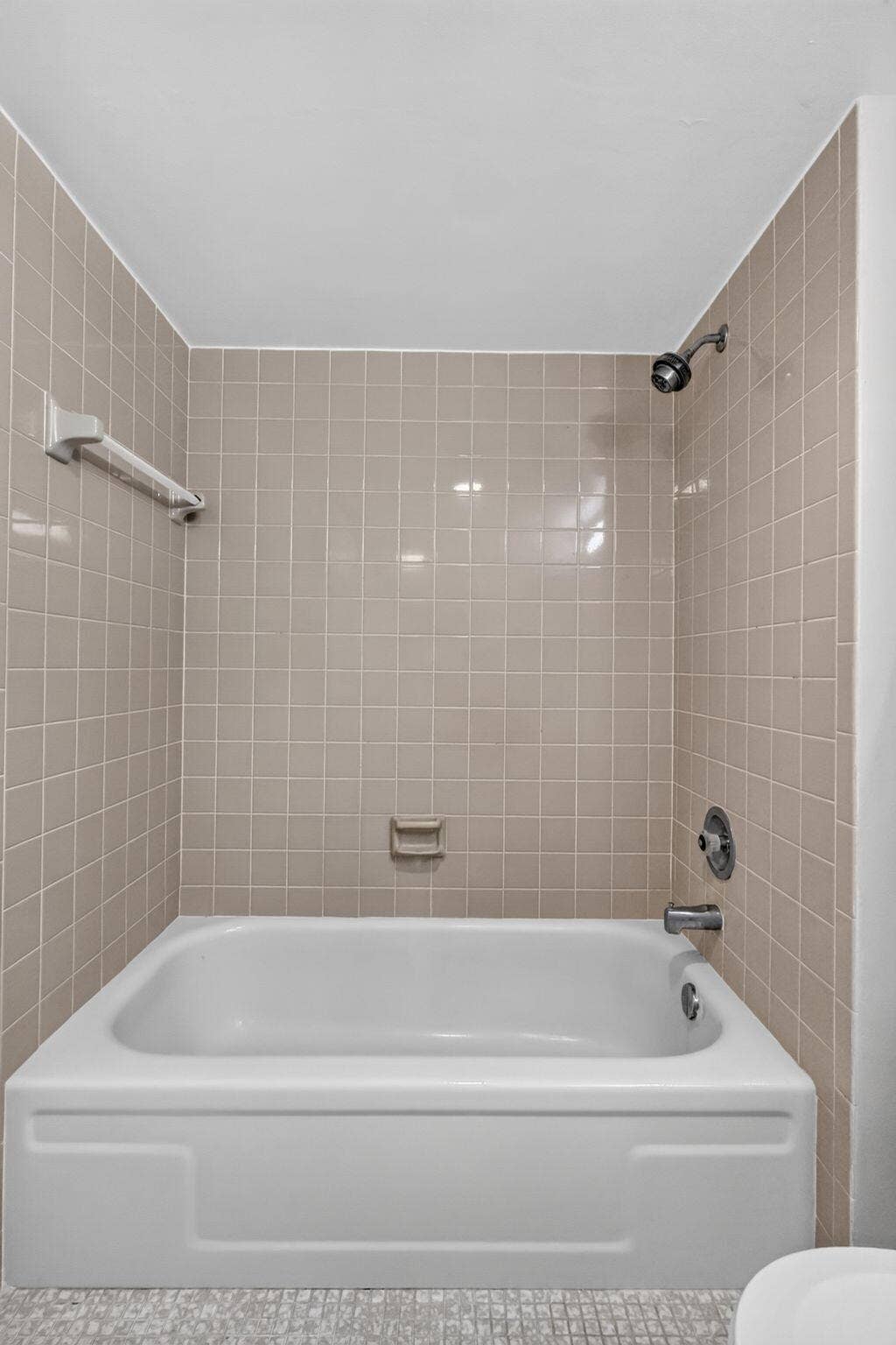14527 BONAIRE Boulevard, #109, Delray Beach, FL 33446 Bathtub surround featuring light-toned square wall tiles, integrated soap dish, chrome shower head, and chrome faucet hardware