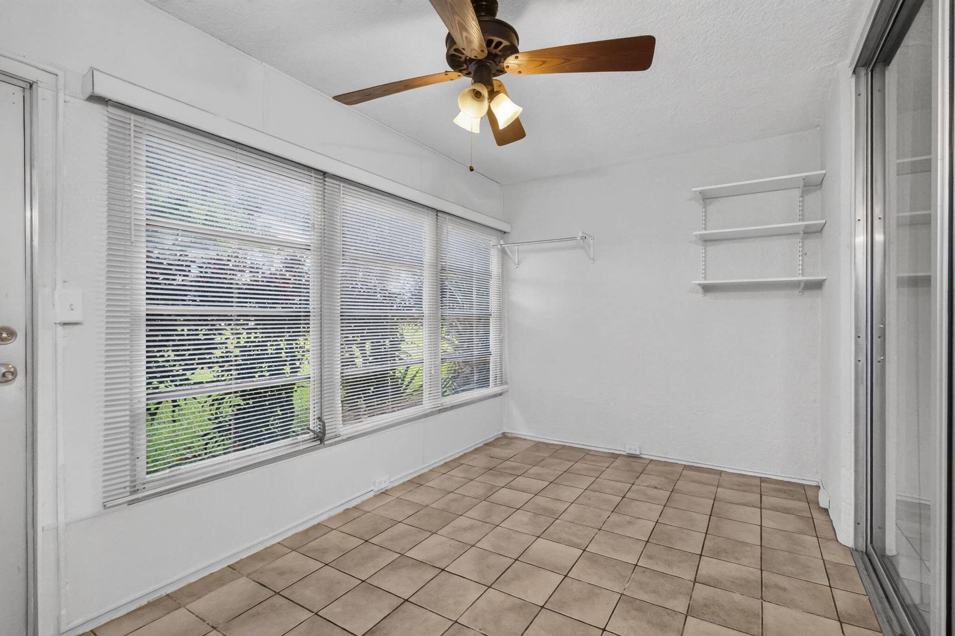 14527 BONAIRE Boulevard, #109, Delray Beach, FL 33446 Sunroom featuring large paneled windows, ceramic tile flooring, a ceiling fan with integrated lighting, wall-mounted shelving, and a metal-frame sliding glass door