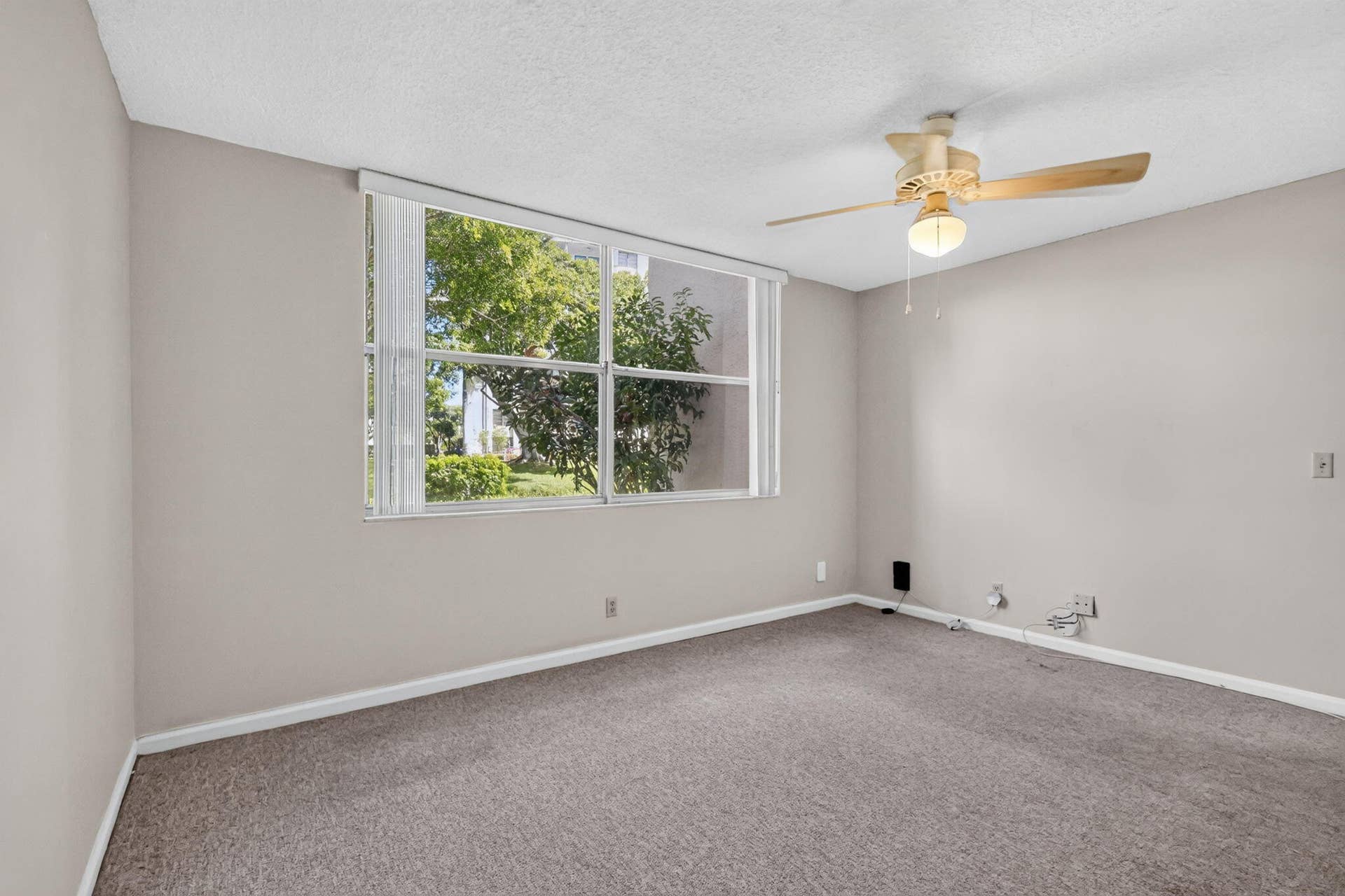 14527 BONAIRE Boulevard, #109, Delray Beach, FL 33446 Neutral interior featuring wall-to-wall carpeting, a multi-pane window with vertical blinds, and a ceiling-mounted fan with integrated lighting
