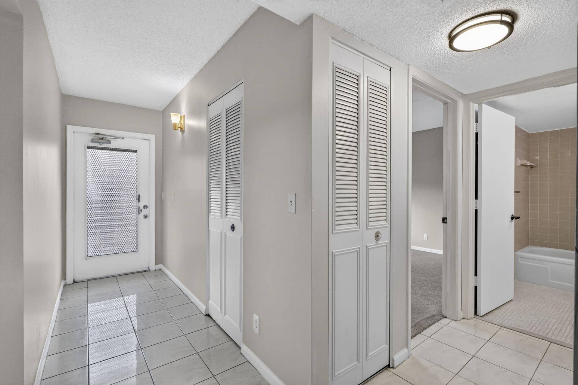 14527 BONAIRE Boulevard, #109, Delray Beach, FL 33446 Entrance foyer featuring large-format ceramic tile flooring, double-panel louvered closet doors, and flush-mount ceiling lighting