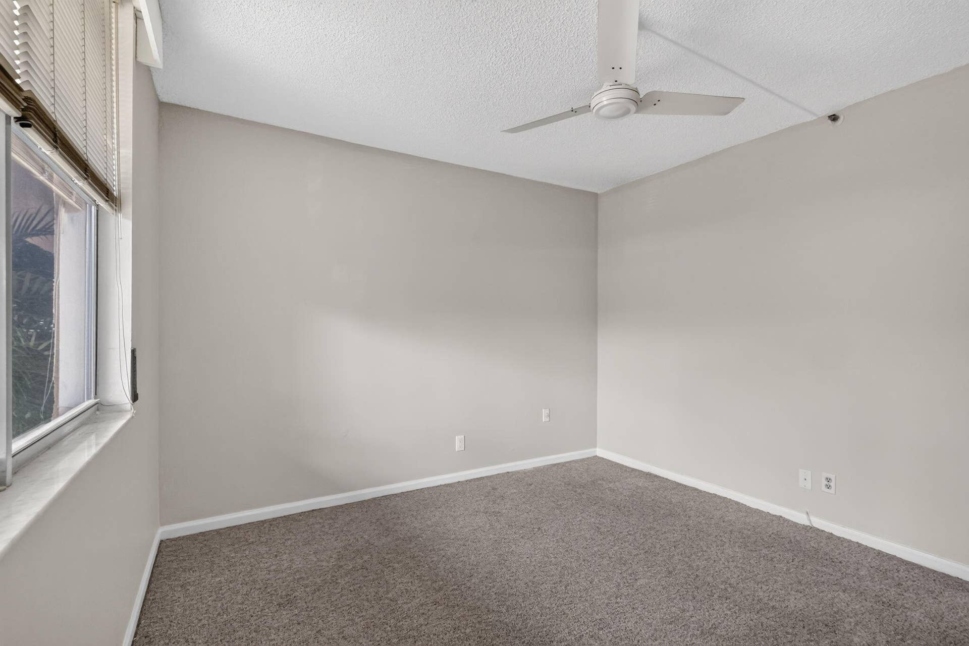 14527 BONAIRE Boulevard, #109, Delray Beach, FL 33446 Neutral-toned interior space featuring wall-to-wall carpeting, a multi-blade ceiling fan, and horizontal window blinds