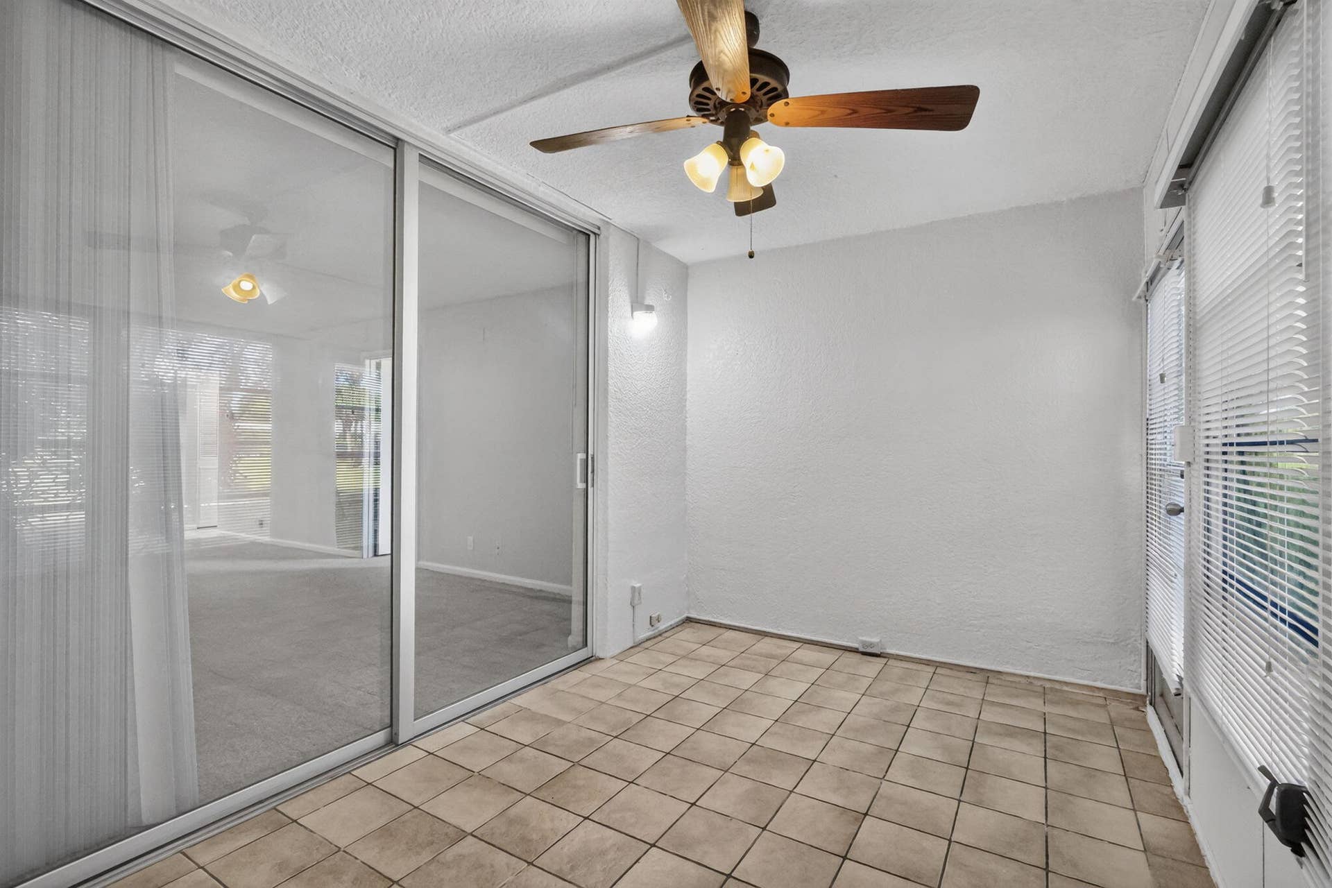 14527 BONAIRE Boulevard, #109, Delray Beach, FL 33446 Enclosed porch featuring ceramic tile flooring, textured wall finishes, a ceiling fan with integrated lighting, and large sliding glass doors