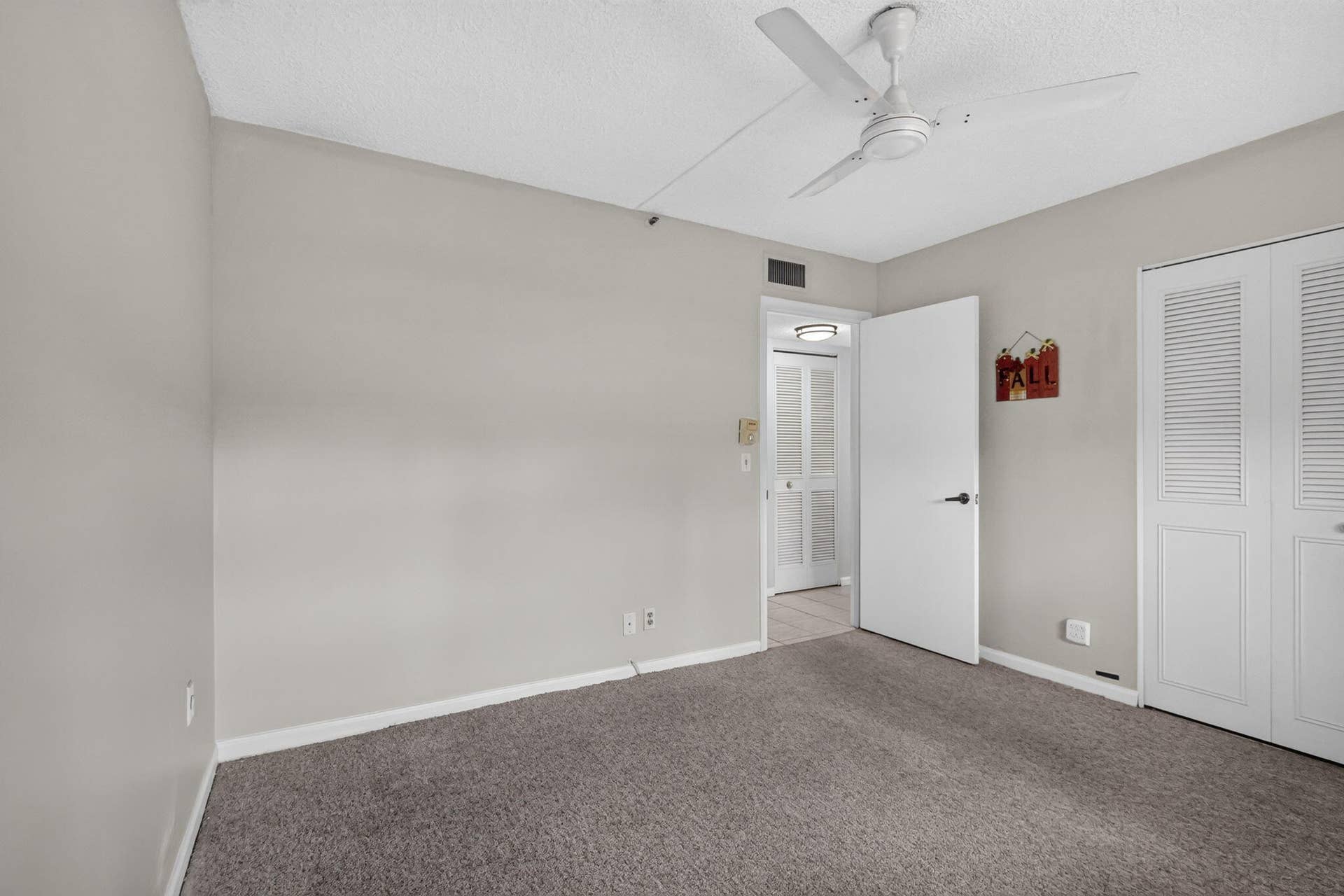 14527 BONAIRE Boulevard, #109, Delray Beach, FL 33446 Neutral-toned interior featuring wall-to-wall carpeting, a white ceiling fan, and double-door louvered closet