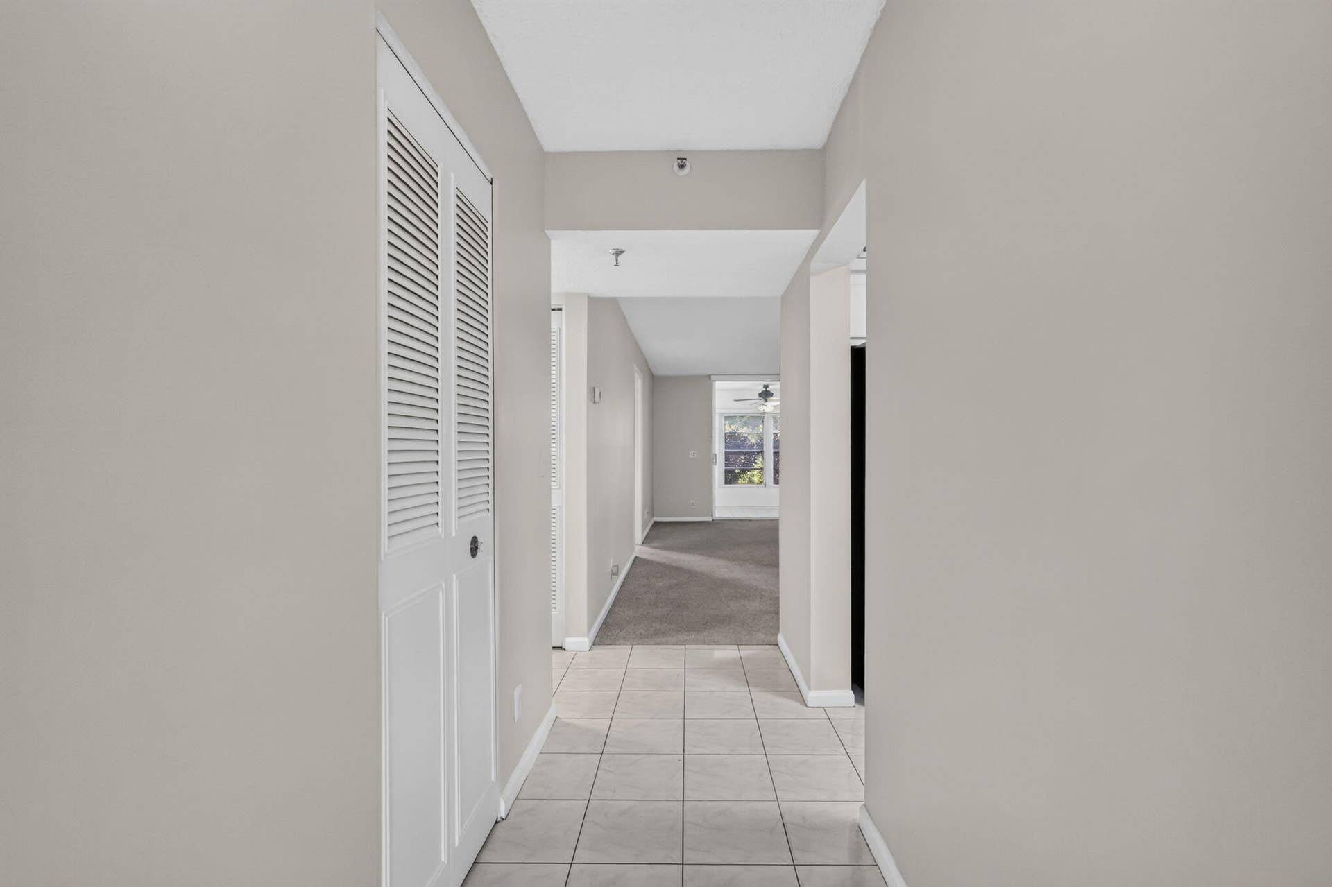 14527 BONAIRE Boulevard, #109, Delray Beach, FL 33446 Hallway featuring light-toned ceramic tile flooring, neutral wall paint, and floor-to-ceiling closet with white louvered double doors