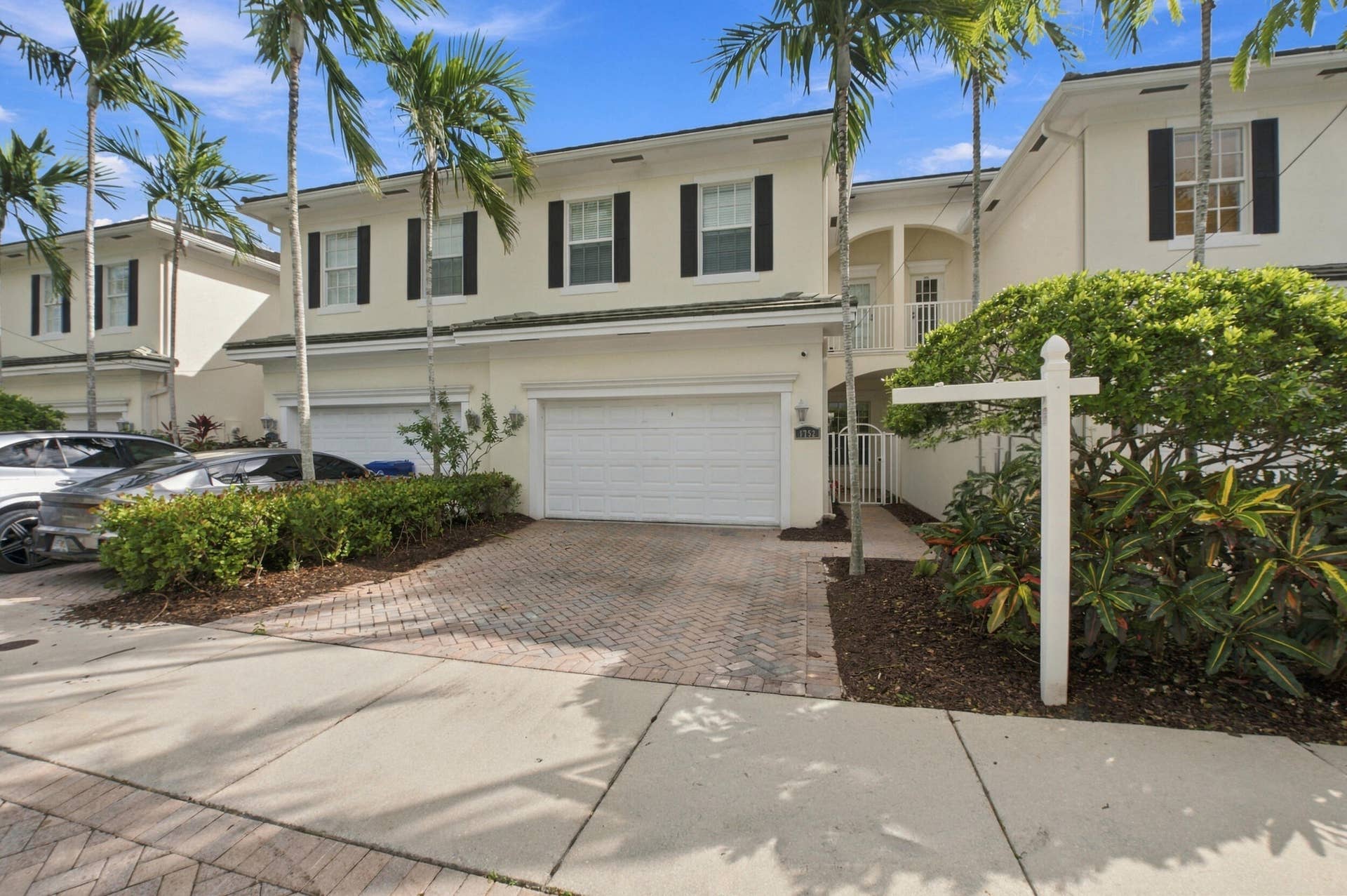 1752 NE 12TH Street, Fort Lauderdale, FL 33304 Two-story exterior featuring light-toned stucco, dark shutters, a paved driveway, and an attached garage