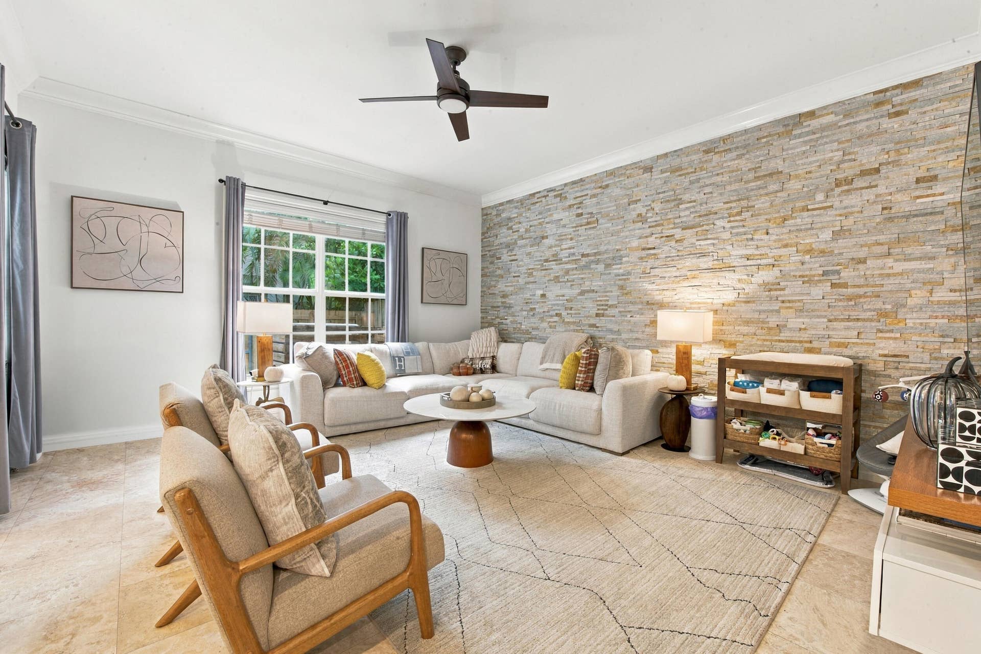 1752 NE 12TH Street, Fort Lauderdale, FL 33304 Living area featuring a stacked stone accent wall, tile flooring, crown molding, and a ceiling fan