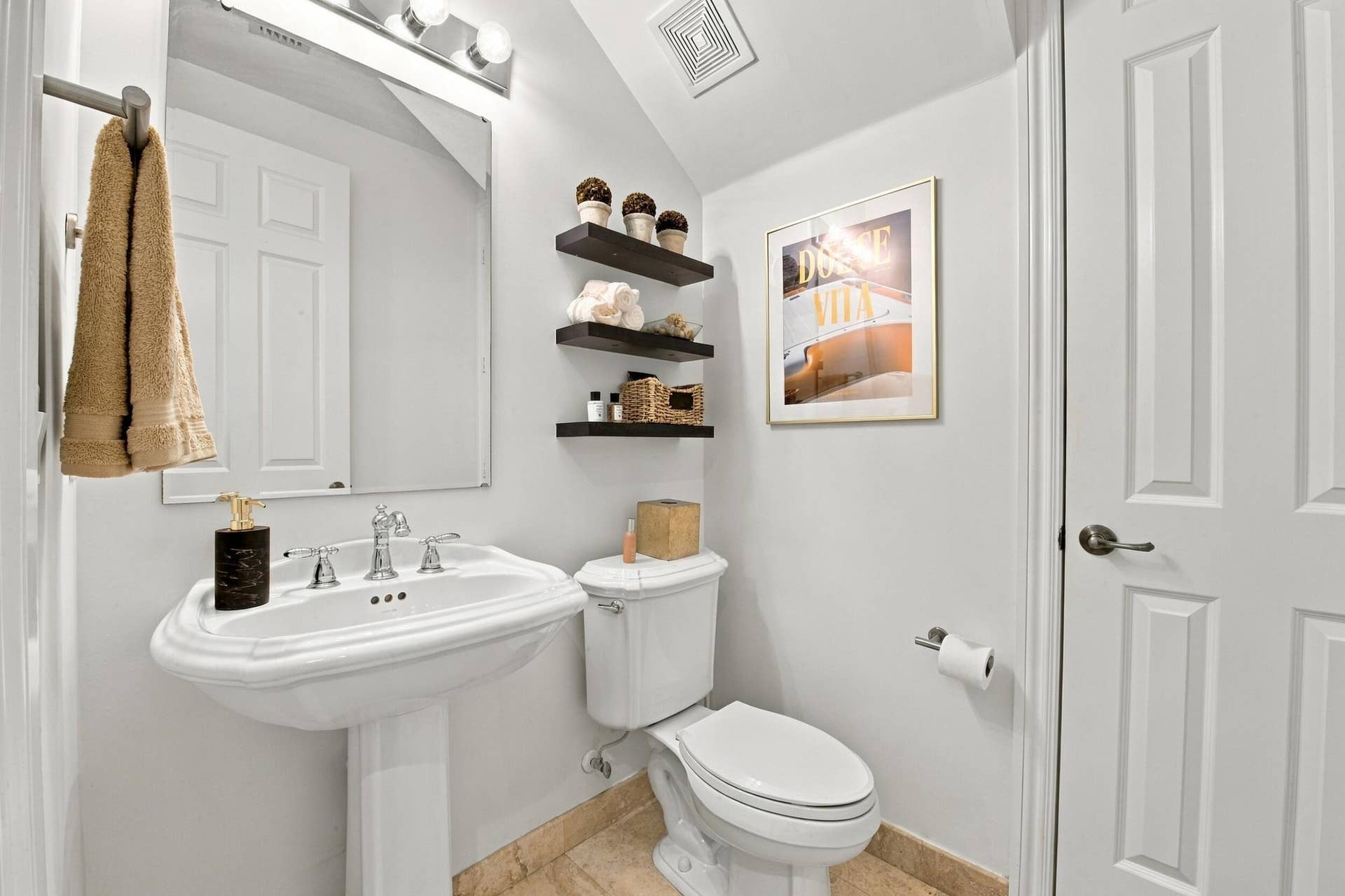 1752 NE 12TH Street, Fort Lauderdale, FL 33304 Pedestal sink featuring a polished chrome faucet, wall-mounted light fixture, mirror, three built-in floating shelves, and stone-finish flooring