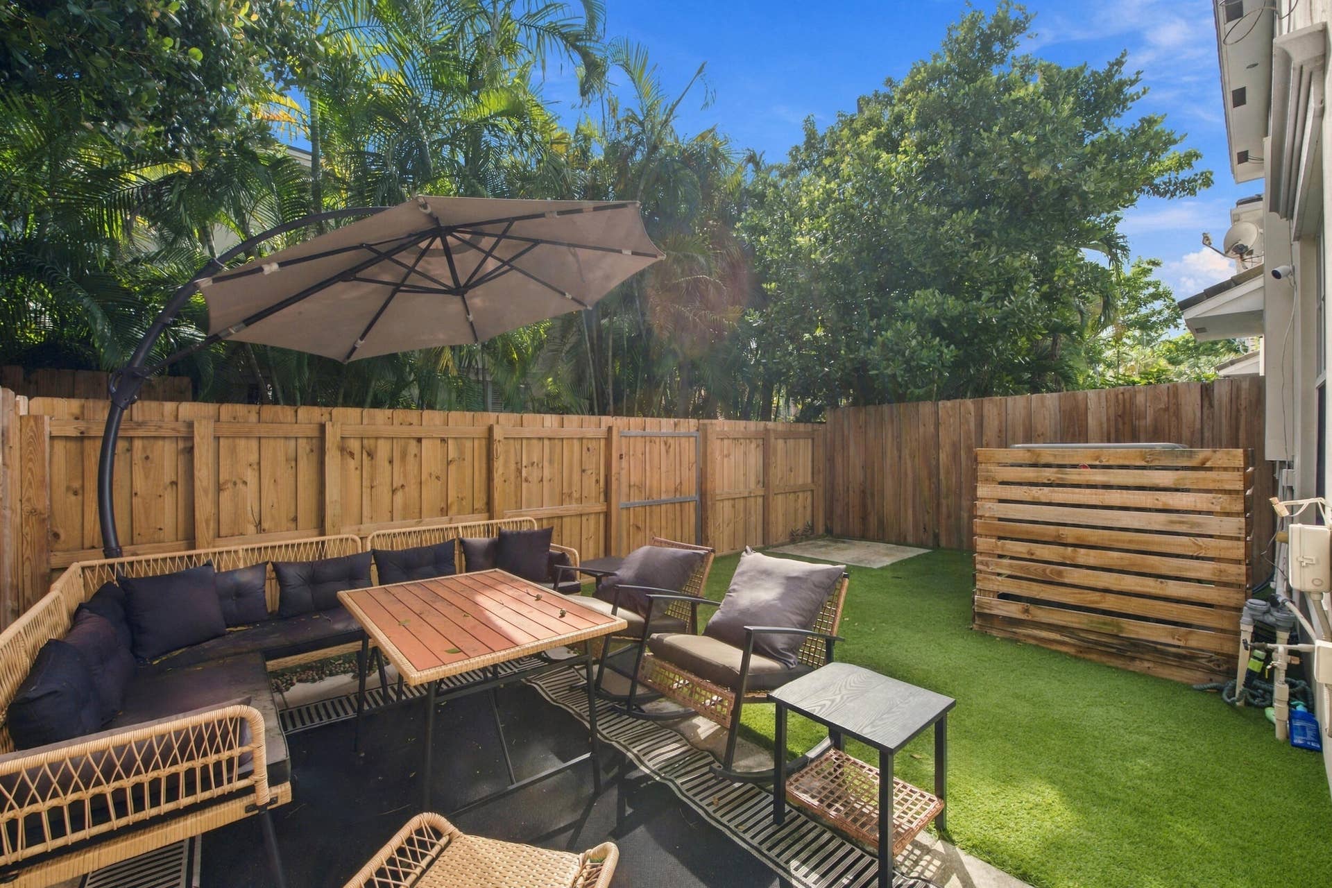 1752 NE 12TH Street, Fort Lauderdale, FL 33304 Private backyard featuring wood-panel fencing, synthetic turf, and mature perimeter trees
