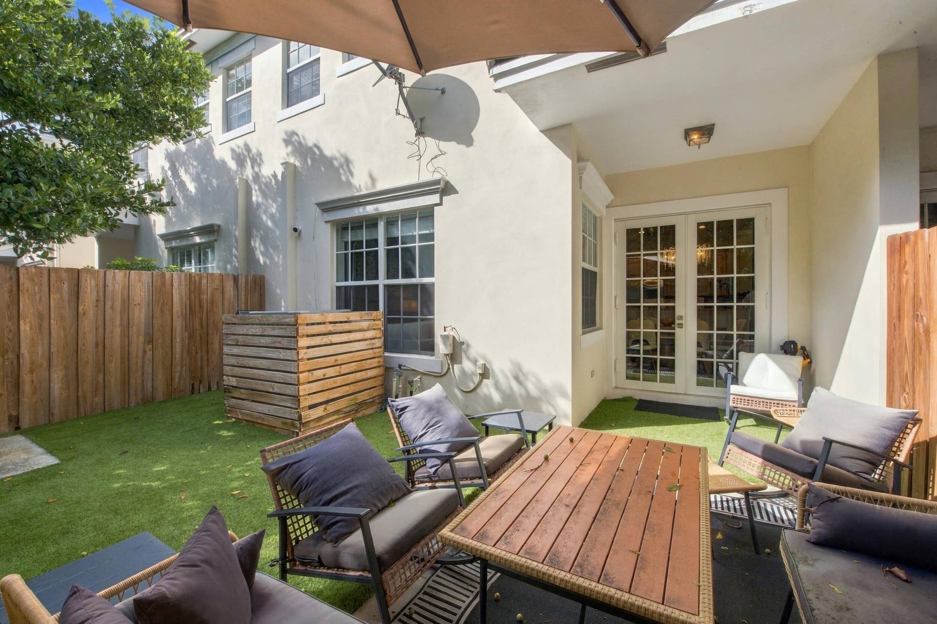 1752 NE 12TH Street, Fort Lauderdale, FL 33304 Private backyard featuring synthetic turf, wood-slat privacy fencing, a covered patio area, and French doors