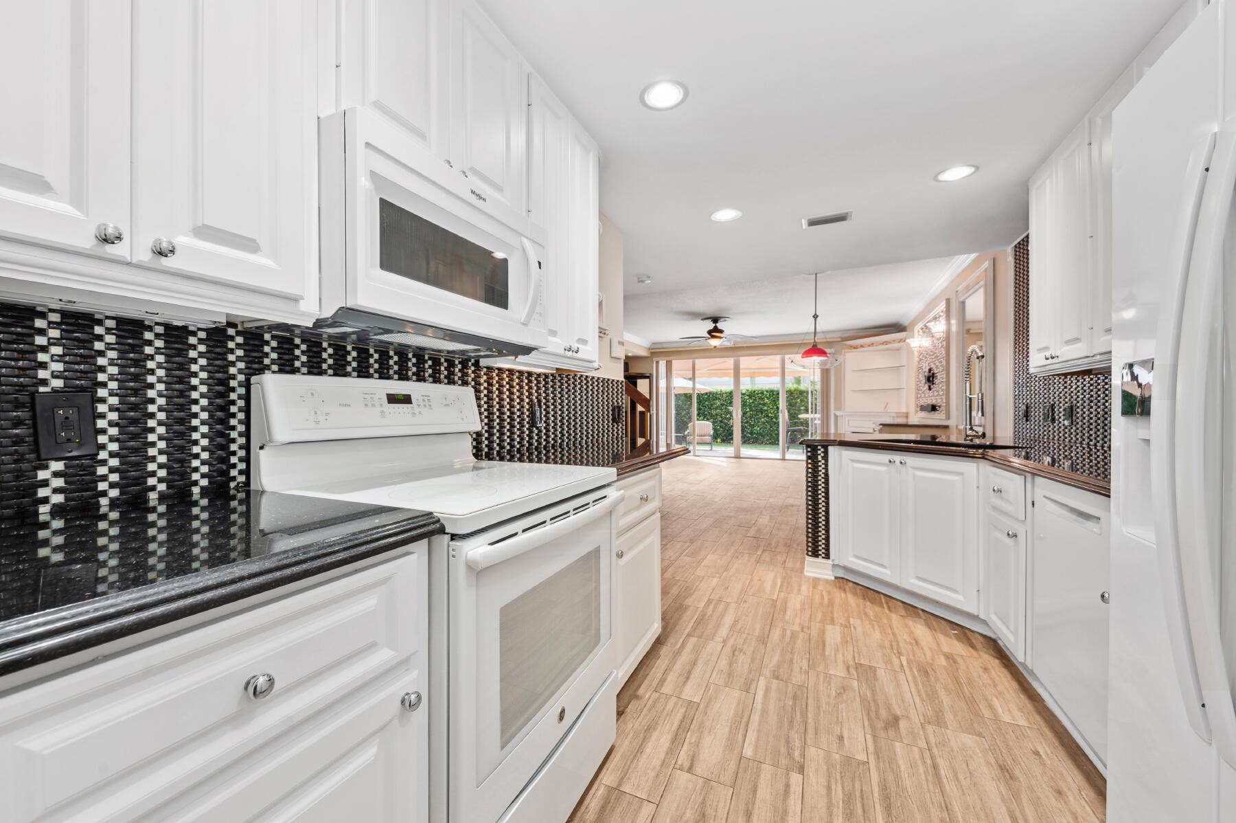 477 Capistrano Drive, Palm Beach Gardens, Palm Beach Gardens, FL 33410 Kitchen featuring white cabinetry, dark countertops, a geometric mosaic tile backsplash, wood-finish flooring, and recessed lighting