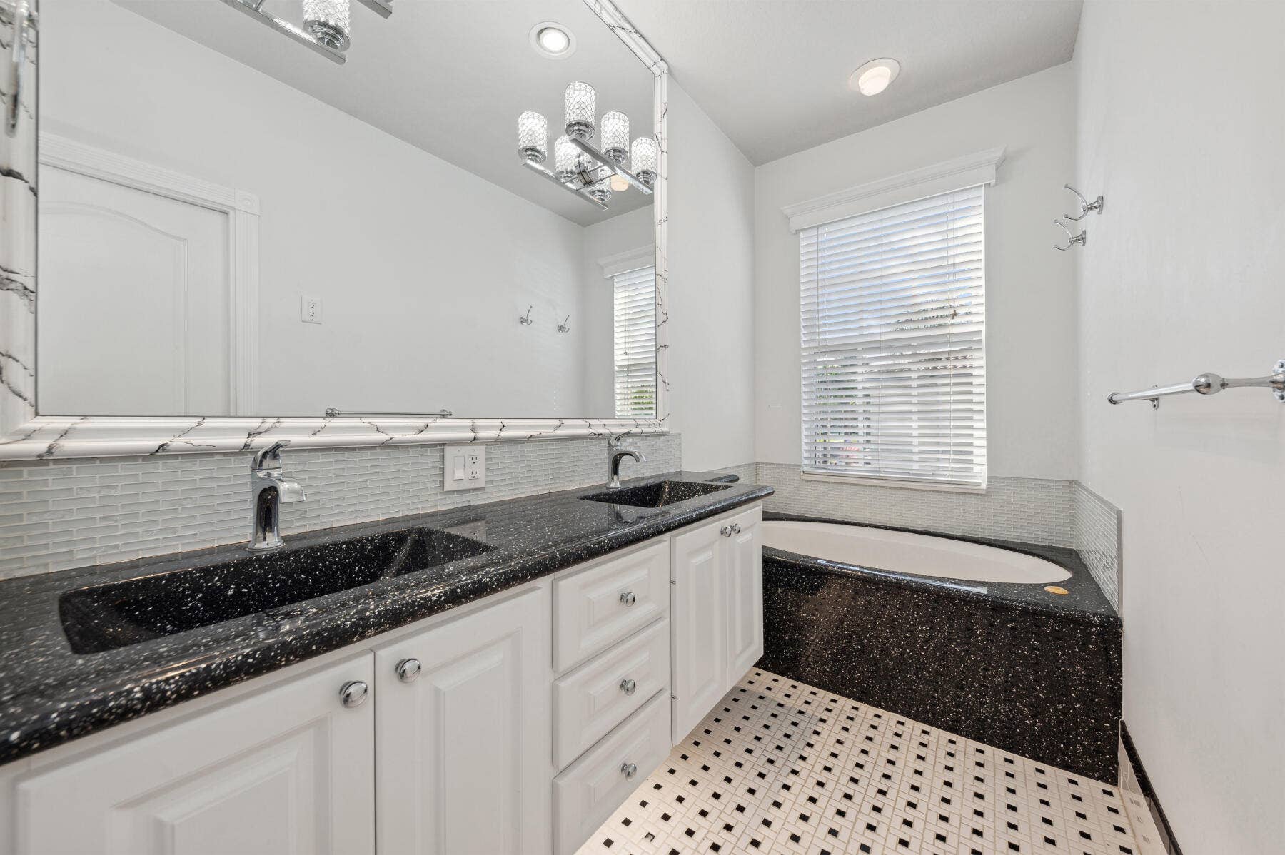 477 Capistrano Drive, Palm Beach Gardens, Palm Beach Gardens, FL 33410 Dual-sink vanity with stone-finish countertops, undermount sinks, white cabinetry, integrated soaking tub, and decorative wall-to-wall mirror with frame detail