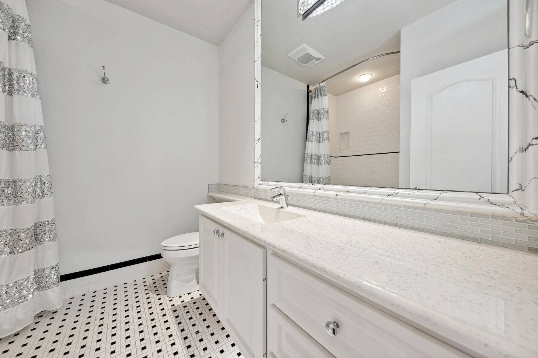 477 Capistrano Drive, Palm Beach Gardens, Palm Beach Gardens, FL 33410 Bathroom featuring a vanity with a light-toned solid surface countertop, an integrated rectangular sink, a large framed mirror, and mosaic-style floor tiling