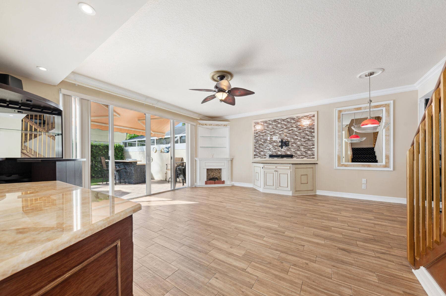 477 Capistrano Drive, Palm Beach Gardens, Palm Beach Gardens, FL 33410 Wood-finish tile flooring, sliding glass doors, corner built-in shelving, custom cabinetry with a stone-finish accent wall, and recessed lighting