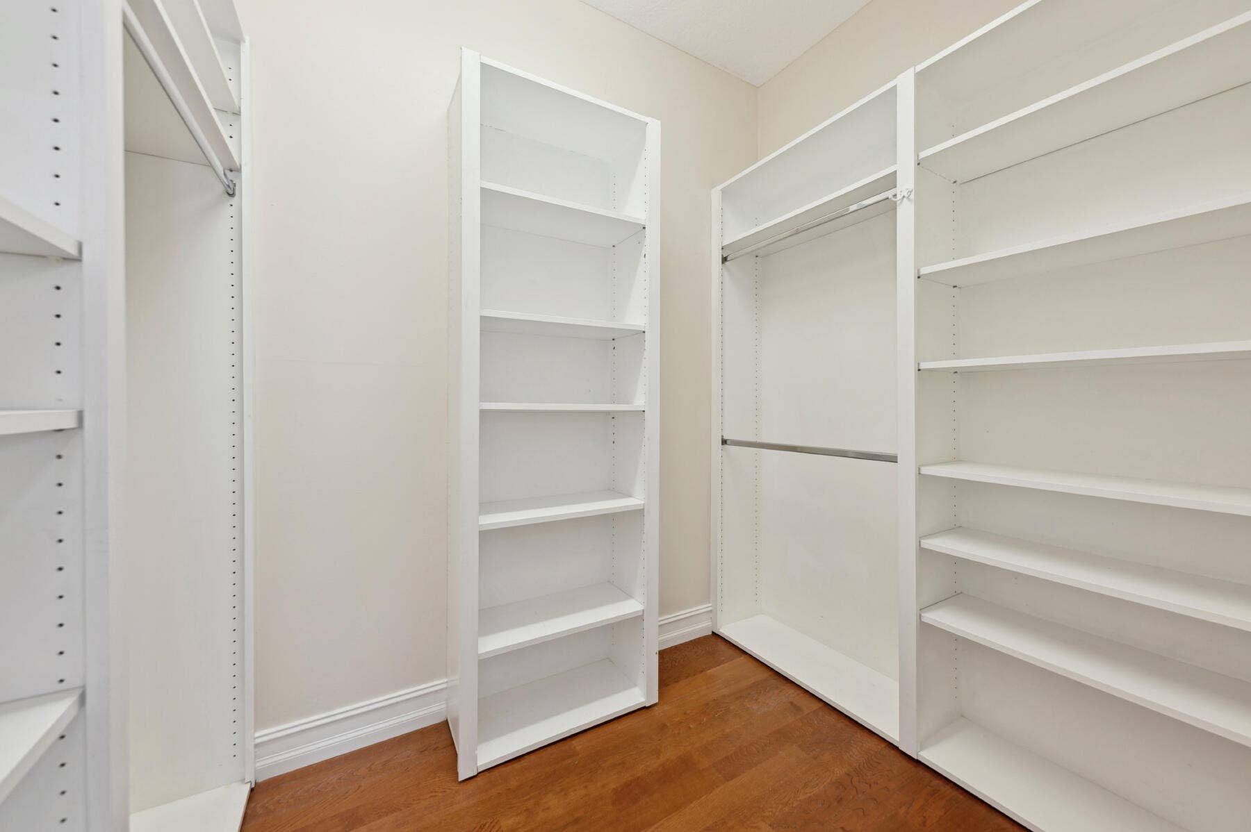 477 Capistrano Drive, Palm Beach Gardens, Palm Beach Gardens, FL 33410 Custom walk-in closet featuring floor-to-ceiling white shelving units, integrated hanging rods, and wood-finish flooring
