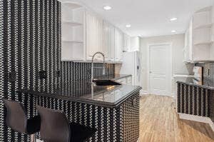 477 Capistrano Drive, Palm Beach Gardens, Palm Beach Gardens, FL 33410 Kitchen featuring white cabinetry, wood-finish flooring, patterned tile backsplash, recessed lighting, and a dark stone-surface countertop with an undermount sink