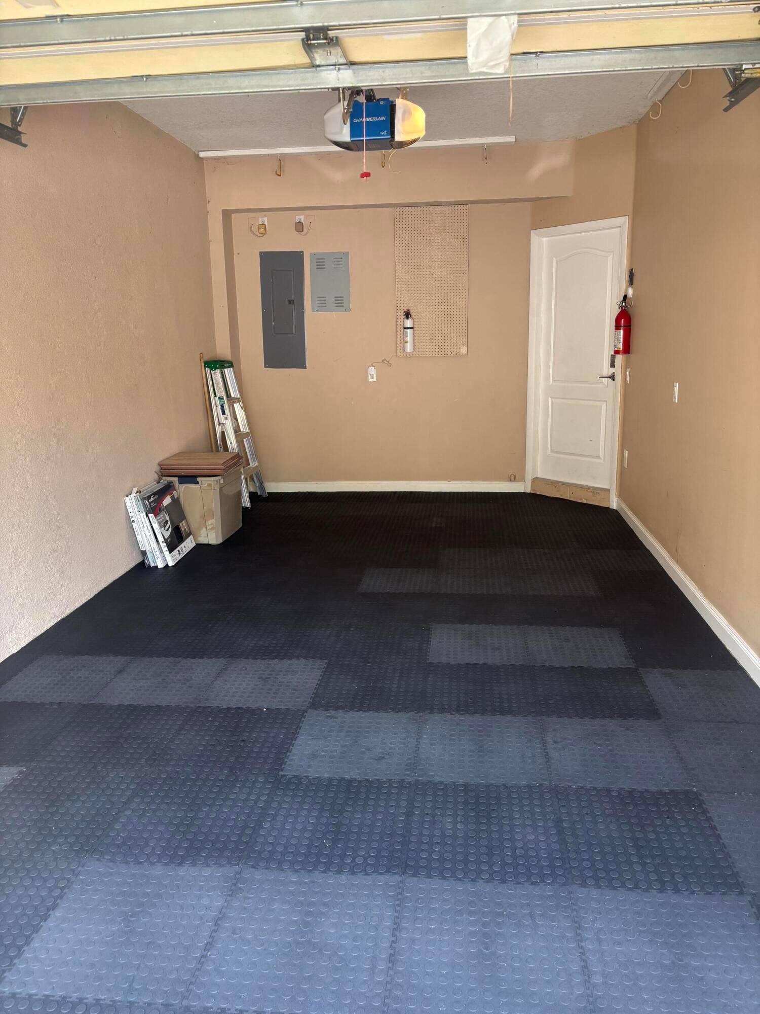 477 Capistrano Drive, Palm Beach Gardens, Palm Beach Gardens, FL 33410 Garage interior featuring modular rubberized flooring, an automated overhead door opener, and a panel-style interior door