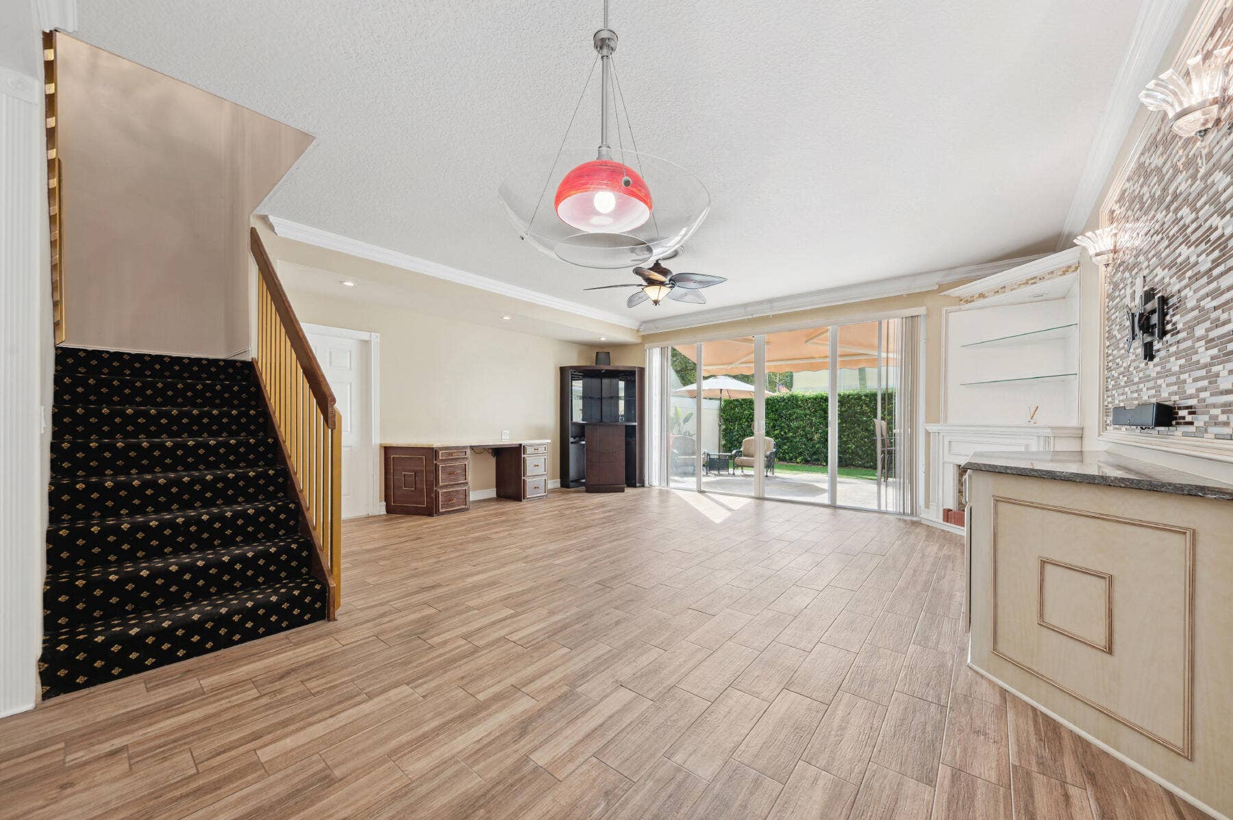 477 Capistrano Drive, Palm Beach Gardens, Palm Beach Gardens, FL 33410 Open-concept interior featuring wood-finish flooring, a built-in stone-top wet bar, floor-to-ceiling glass sliding doors, and a decorative tile accent wall
