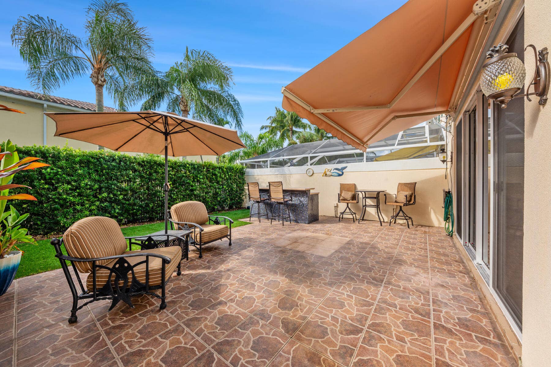 477 Capistrano Drive, Palm Beach Gardens, Palm Beach Gardens, FL 33410 Outdoor patio featuring stone-patterned tile, a built-in stone-finished wet bar, a retractable awning, and integrated wall-mounted lighting
