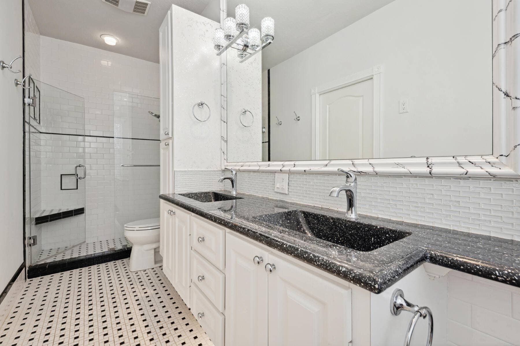 477 Capistrano Drive, Palm Beach Gardens, Palm Beach Gardens, FL 33410 Double vanity with dark speckled countertop and integrated sinks, white cabinetry, glass-enclosed shower with subway tile surround, and mosaic tile flooring