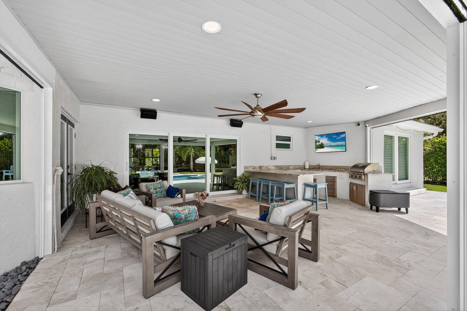 4628 Square Lake Drive, Palm Beach Gardens, FL 33418 Covered outdoor living space featuring natural stone flooring, tongue-and-groove ceiling, recessed lighting, and a built-in outdoor kitchen with a stainless steel grill