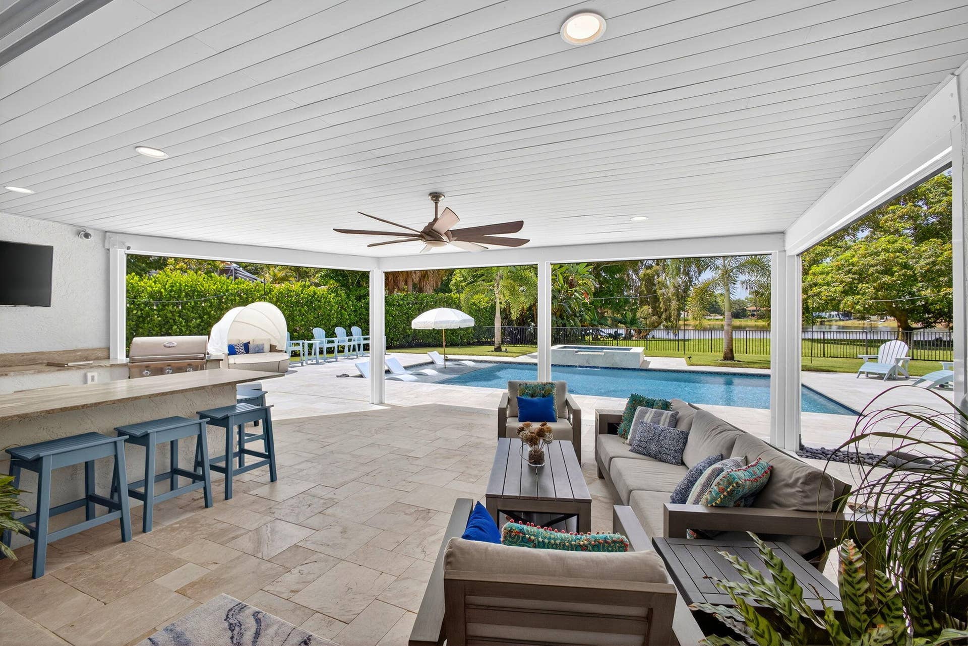 4628 Square Lake Drive, Palm Beach Gardens, FL 33418 Covered patio featuring a built-in outdoor kitchen with stone countertops, recessed lighting, ceiling fan, and stone paver flooring overlooking an in-ground swimming pool and spa