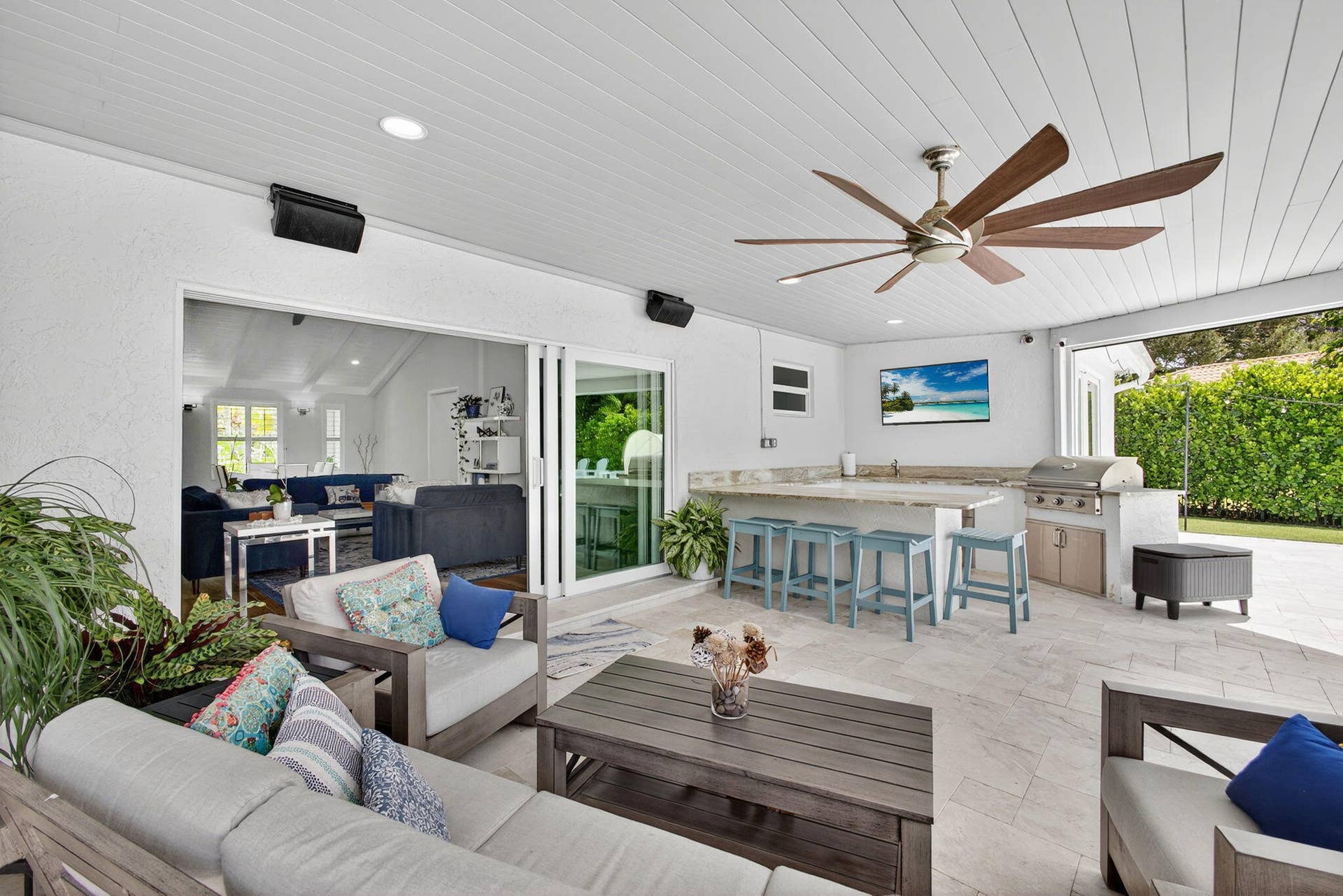 4628 Square Lake Drive, Palm Beach Gardens, FL 33418 Covered patio featuring large-format stone flooring, tongue-and-groove ceiling, multi-blade ceiling fan, and built-in outdoor kitchen with stone countertop and stainless steel grill