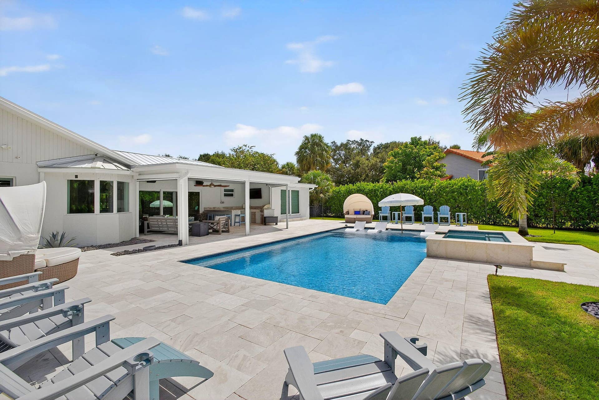 4628 Square Lake Drive, Palm Beach Gardens, FL 33418 Outdoor living area featuring a covered patio, a rectangular swimming pool, an elevated integrated spa, stone-paver decking, and manicured landscaping