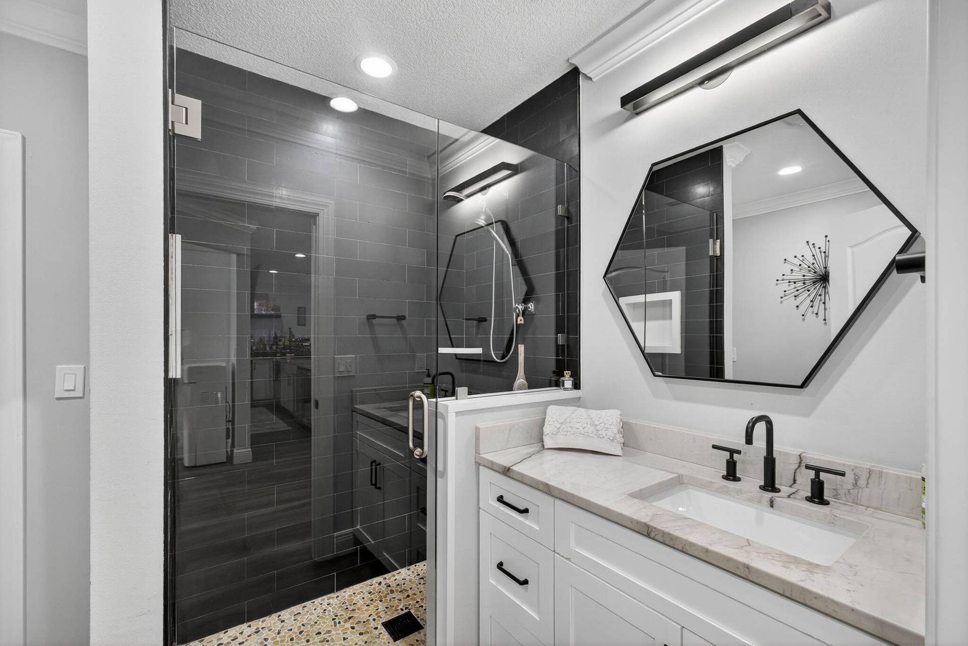 4628 Square Lake Drive, Palm Beach Gardens, FL 33418 Bathroom featuring a vanity with stone countertop, rectangular undermount sink, and matte black widespread faucet, paired with a walk-in shower enclosed by glass and finished with dark tile and a mosaic-tiled floor