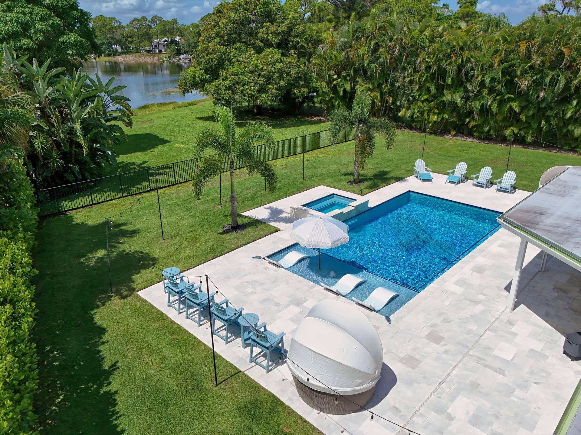 4628 Square Lake Drive, Palm Beach Gardens, FL 33418 Backyard featuring an in-ground swimming pool with a tanning ledge, an integrated spa, stone-finish pool decking, and waterfront positioning