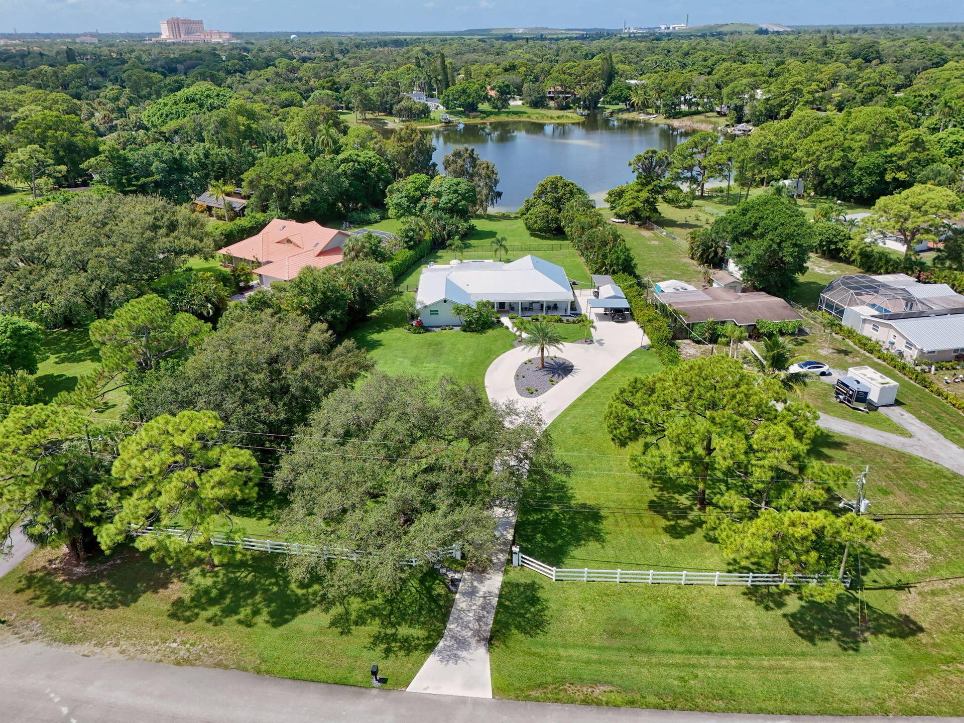 4628 Square Lake Drive, Palm Beach Gardens, FL 33418 Aerial perspective of a sprawling lot featuring a gated entrance, expansive green space, mature trees, a curved concrete driveway, and direct water frontage