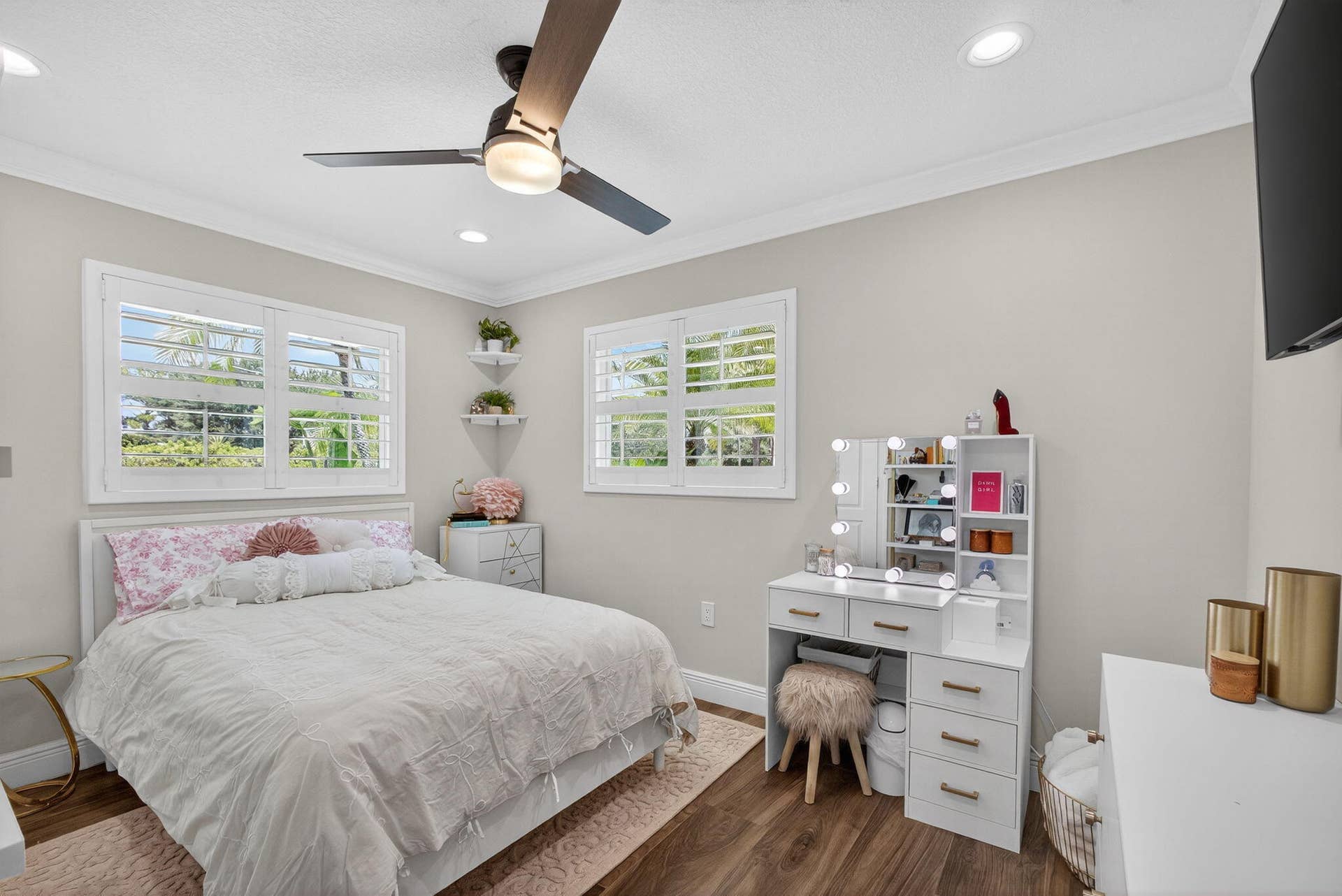 4628 Square Lake Drive, Palm Beach Gardens, FL 33418 Room featuring wood-finish flooring, plantation shutters, crown molding, built-in corner shelving, and a multi-blade ceiling fan