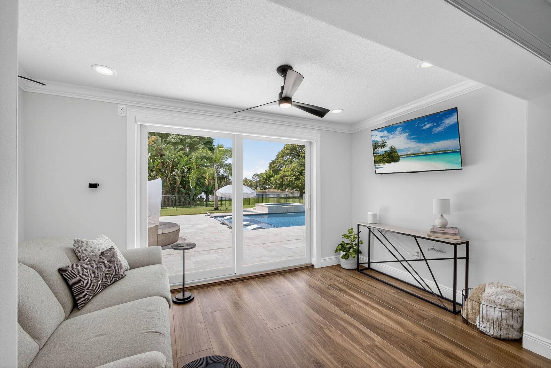 4628 Square Lake Drive, Palm Beach Gardens, FL 33418 Wood-finish flooring, recessed lighting, modern three-blade ceiling fan, and sliding glass doors revealing a paved patio and swimming pool