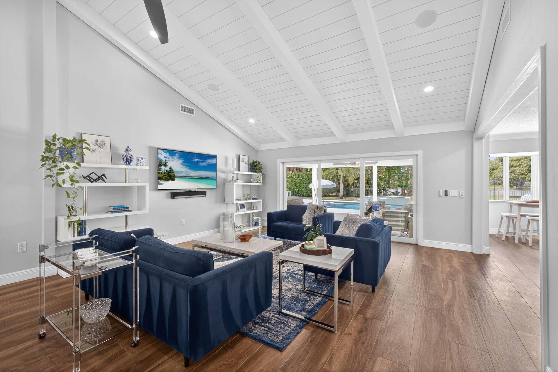 4628 Square Lake Drive, Palm Beach Gardens, FL 33418 Vaulted ceiling featuring exposed beams and tongue-and-groove paneling, wide-plank wood-finish flooring, built-in shelving, and floor-to-ceiling sliding glass doors