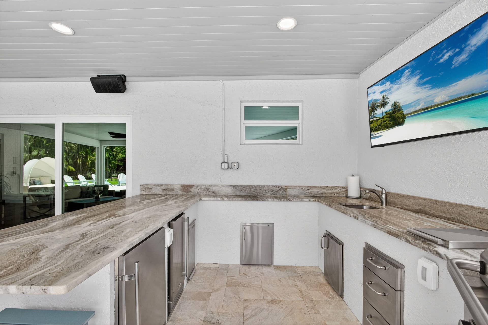 4628 Square Lake Drive, Palm Beach Gardens, FL 33418 Outdoor kitchen featuring stone-finish countertops, stainless steel cabinetry, under-counter refrigeration, a built-in sink, and tile flooring